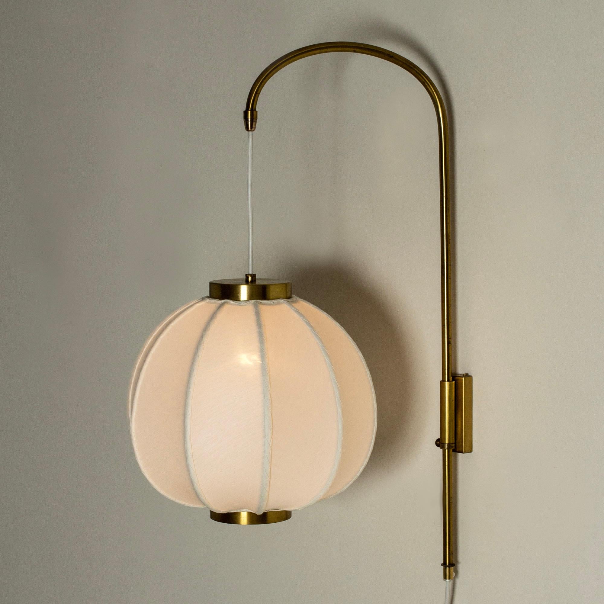 Rare, beautiful wall light by Josef Frank, made from brass with a slender stem suspending a voluminous lamp shade. Adjustable height.