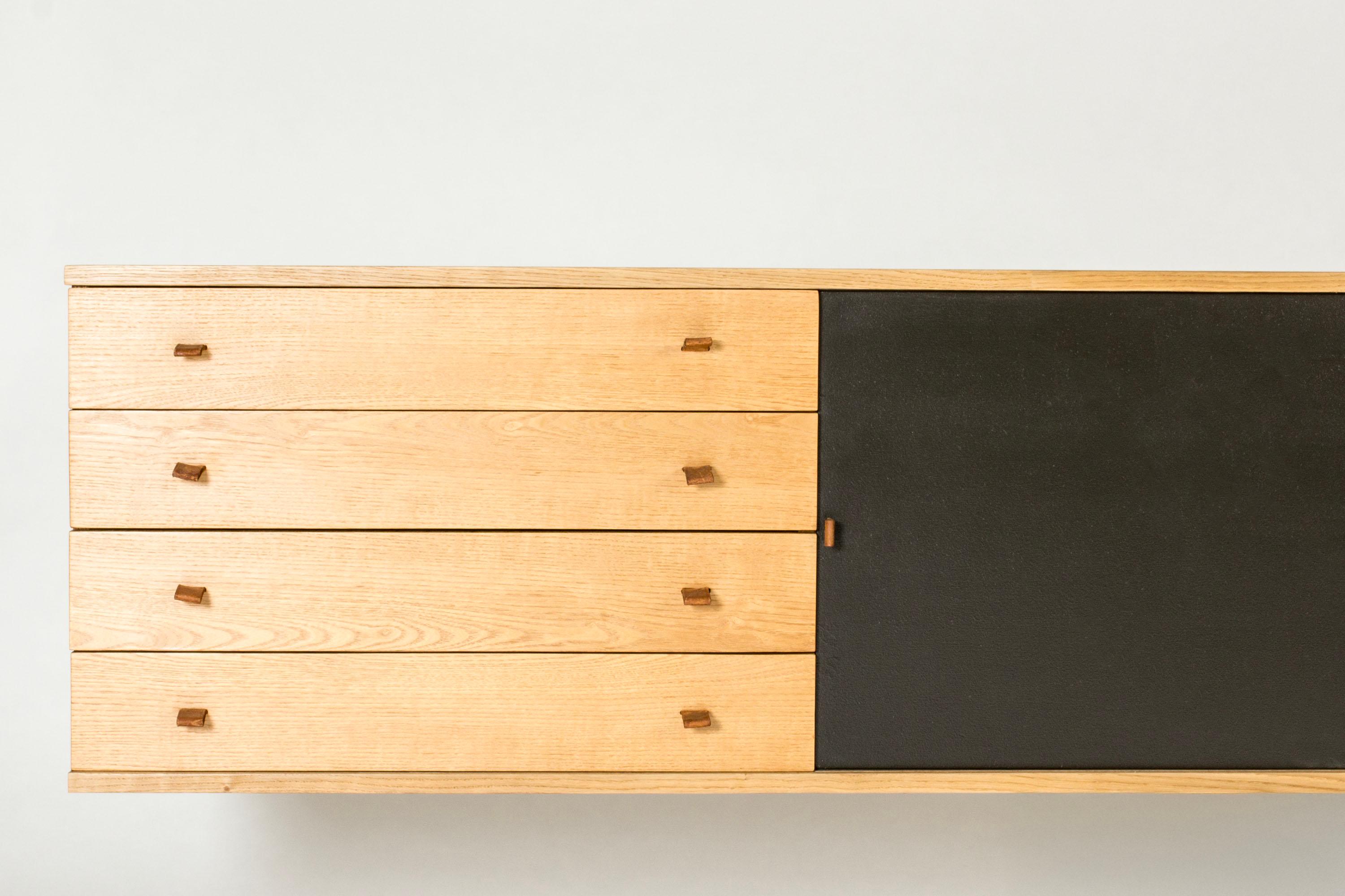 Wall mounted sideboard by Harbo Sølvsten, in a long, sleek design. Made fr0m oak with contrasting black lacquered doors and decorative leather handles.