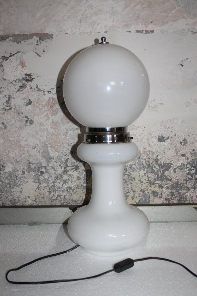 Mid-Century Modern white glass table lamp by Mazzega, Italy '60

 Flattened white opal hand blown crystal Murano glass base and white opal bulb style glass globe on top. Chromed metal (iron) ring. This Mazzega white table lamp is often named Mezzo