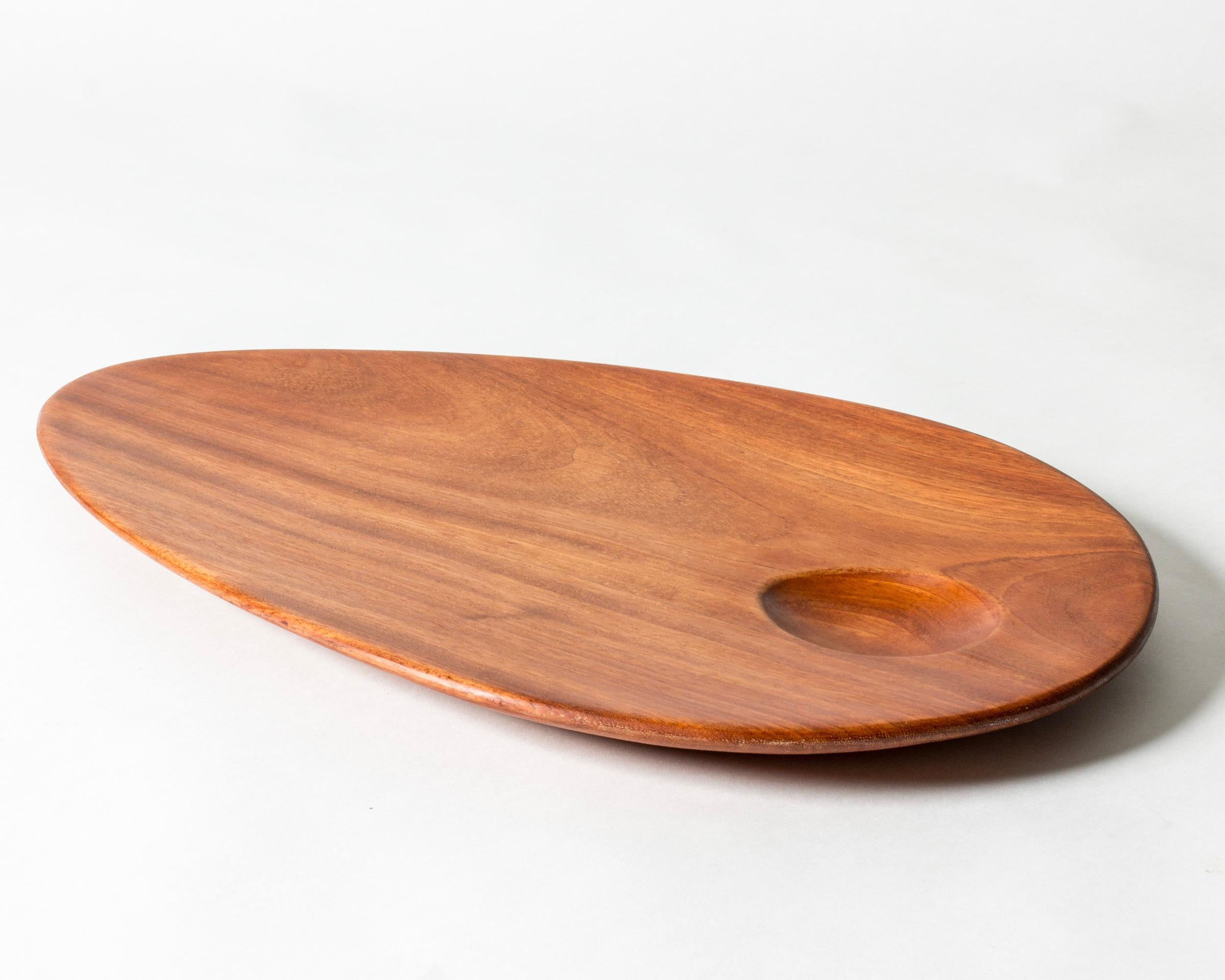 Bellissimo piatto da portata di Sakari Pykälä, realizzato in teak in una forma ovale e liscia. Un incavo nel legno crea un bel dettaglio.
