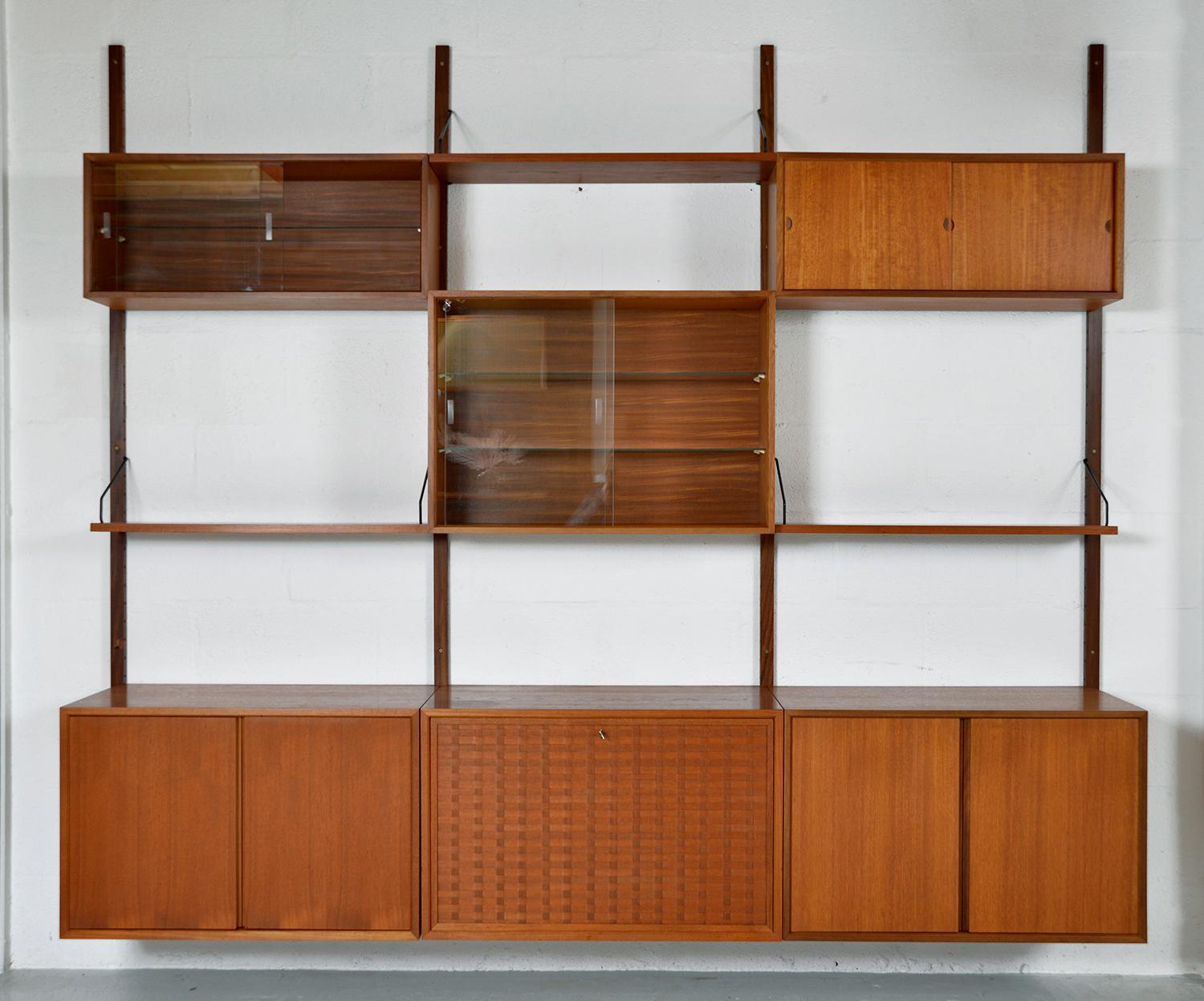This highly versatile and functional “Royal System”, originally designed by Poul Cadovius in 1948, offers a wide variety of storage and display options. 
This particular modular arrangement comprises 4 uprights, 3 shelves, 2 glass-fronted cabinets