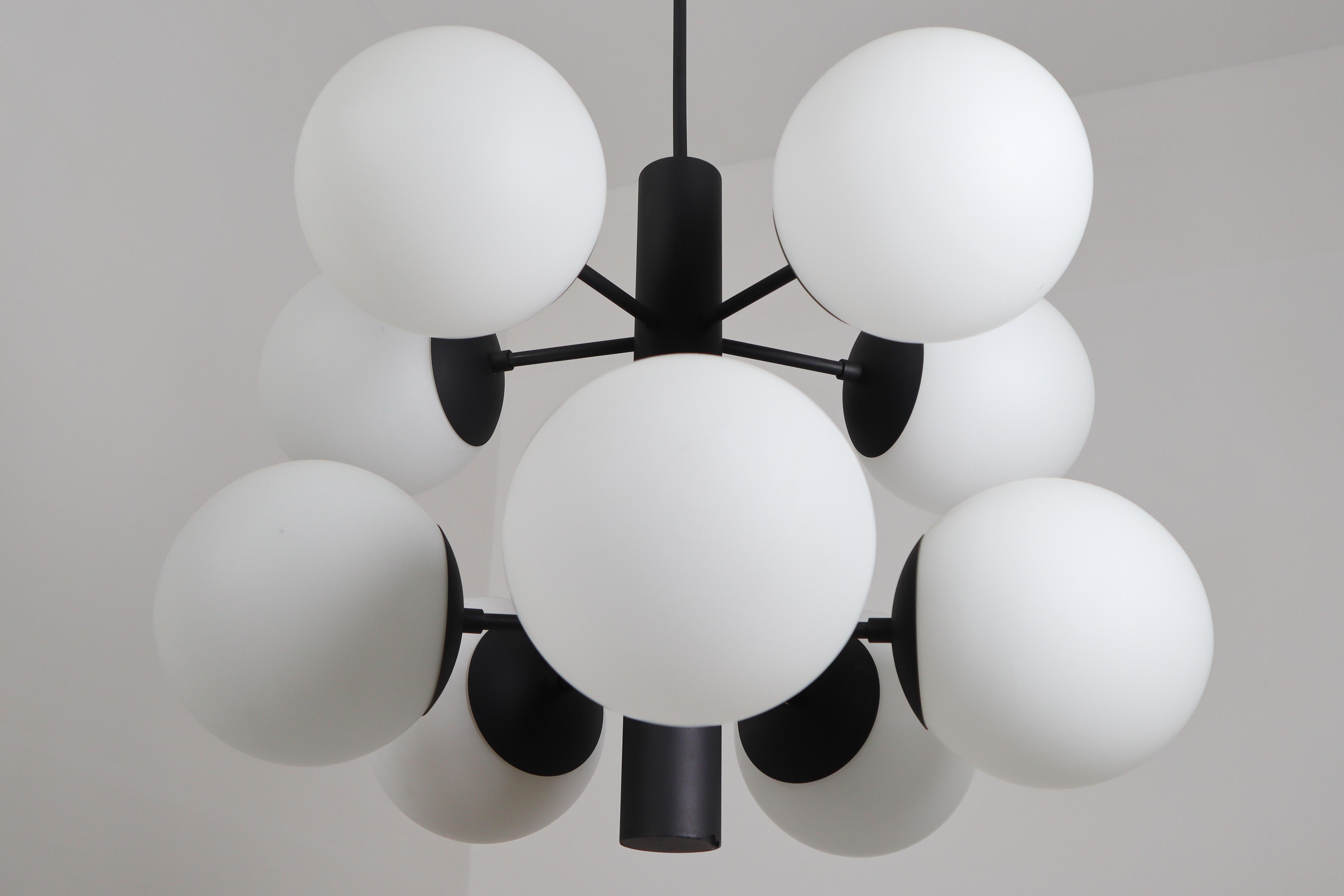 These fantastic midcentury molecular structure chandeliers was designed in Germany 1960s featuring a black coated brass frame and ten hand blown opal glass globes. Ten opaline glass globes are placed over two levels. A warm and diffuse light will
