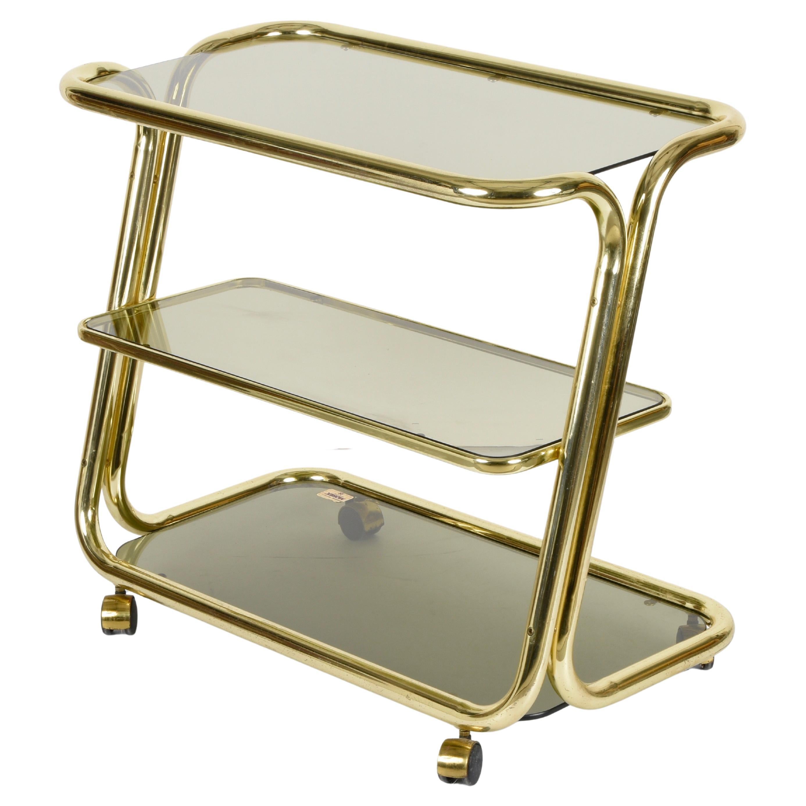Exceptional mid-century brass and three-levelled smoked glass bar cart. This fantastic service cart was produced by Morex in Italy during the 1970s.

The elegance of this wonderful piece is due to the tubular, space-age and delicate shiny brass