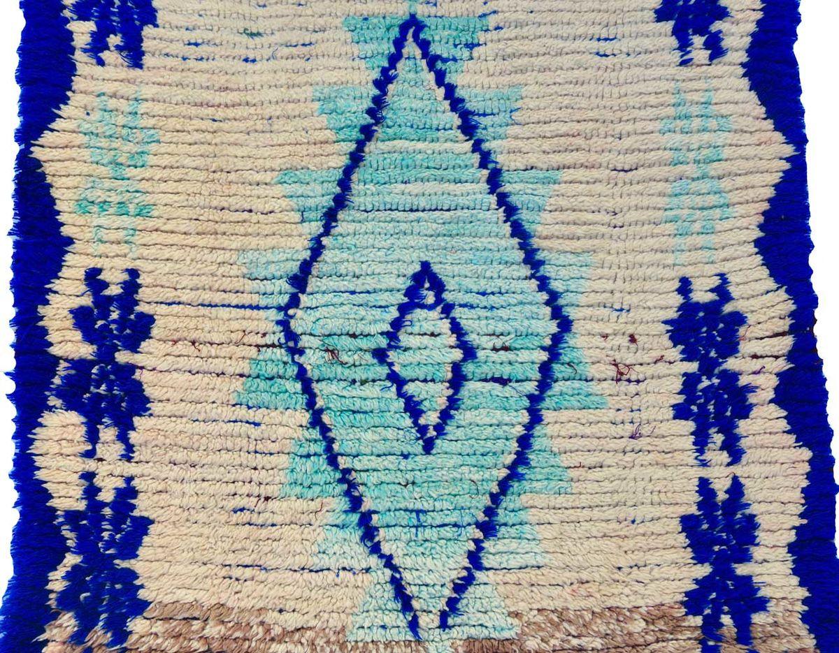 Marokkanischer Läufer, handgewebt in üppigen Ecru-, Aqua- und Indigofarbtönen mit Berbersymbolen und olivgrünen Quasten.
Abmessungen: 3'11 x 8'4