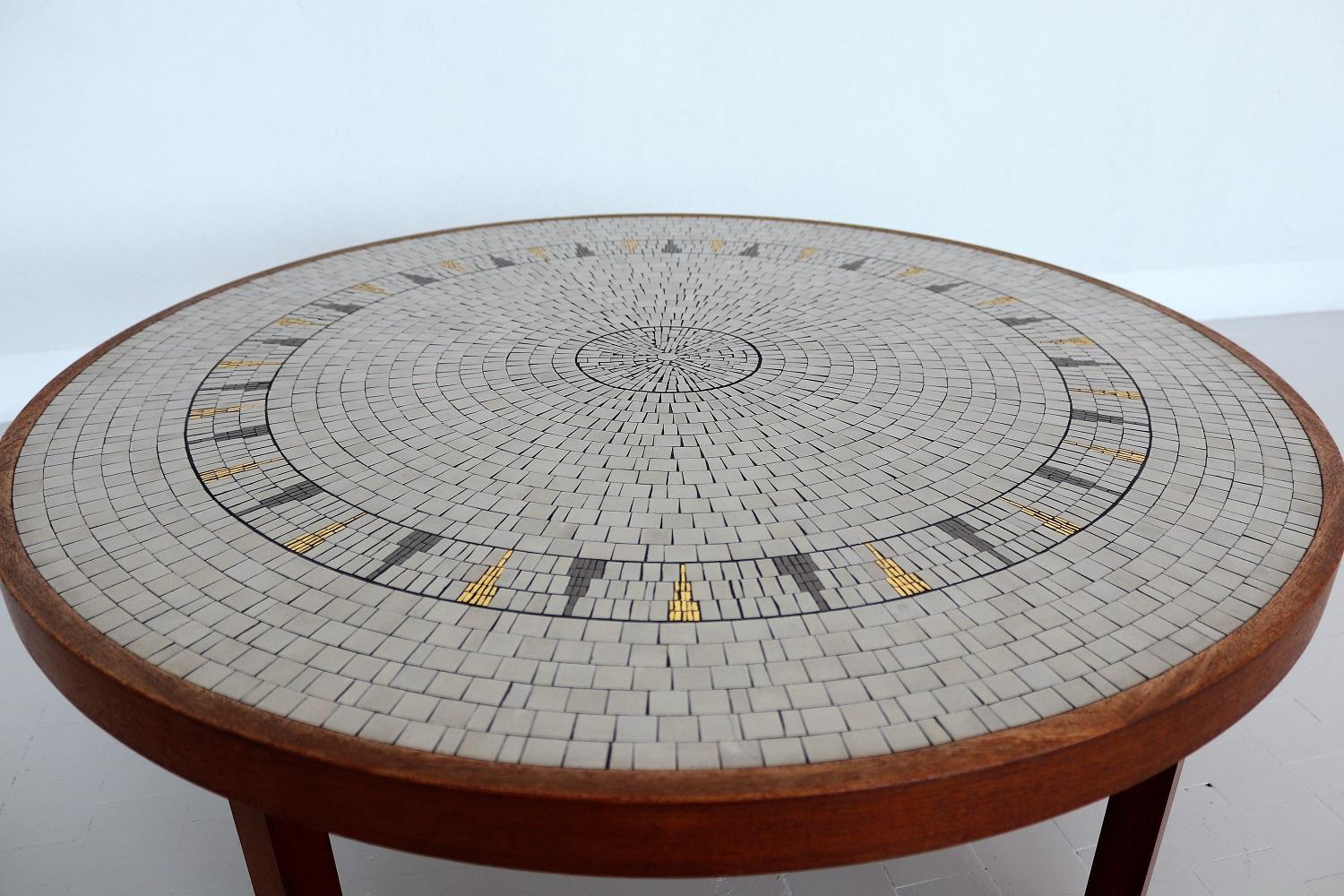 Gorgeous coffee table with big mosaic plate with white-off, grey and golden tiles on strong teak table base.
The golden tiles are shining beautifully in the light!
Made in Germany in the 1960s by Berthold Müller, Oerlighausen.
The mosaic as well as
