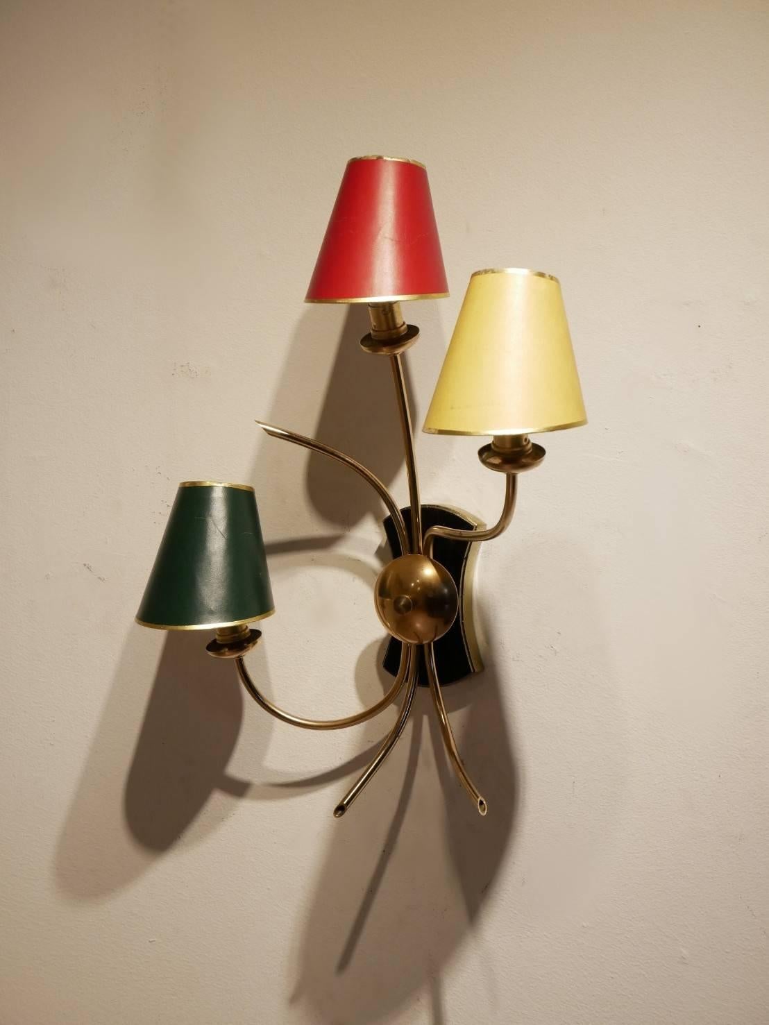 Midcentury French wall sconce in the shape of a small tree, organic bent brass structure matched with black and gold painted wooden wall mount base, original tricolor red / yellow / green paper clip-on shades.