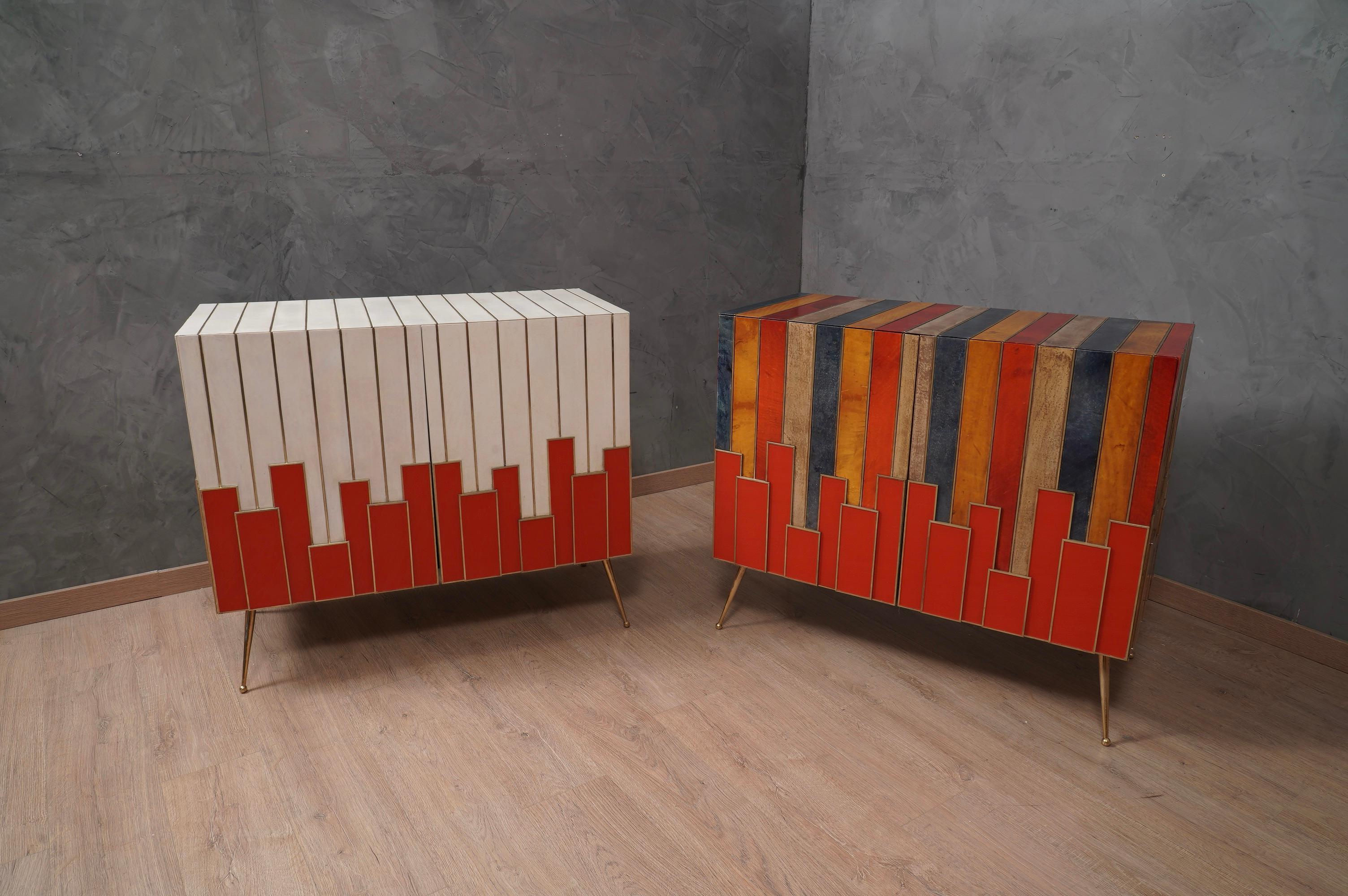 Precious materials such as multicolor goatskin, brass and red glass stage an elegant sideboards of the middle of the century, one of a kind design. The contrast between the multicolor of the parchment and the red of the glass is very nice.

The