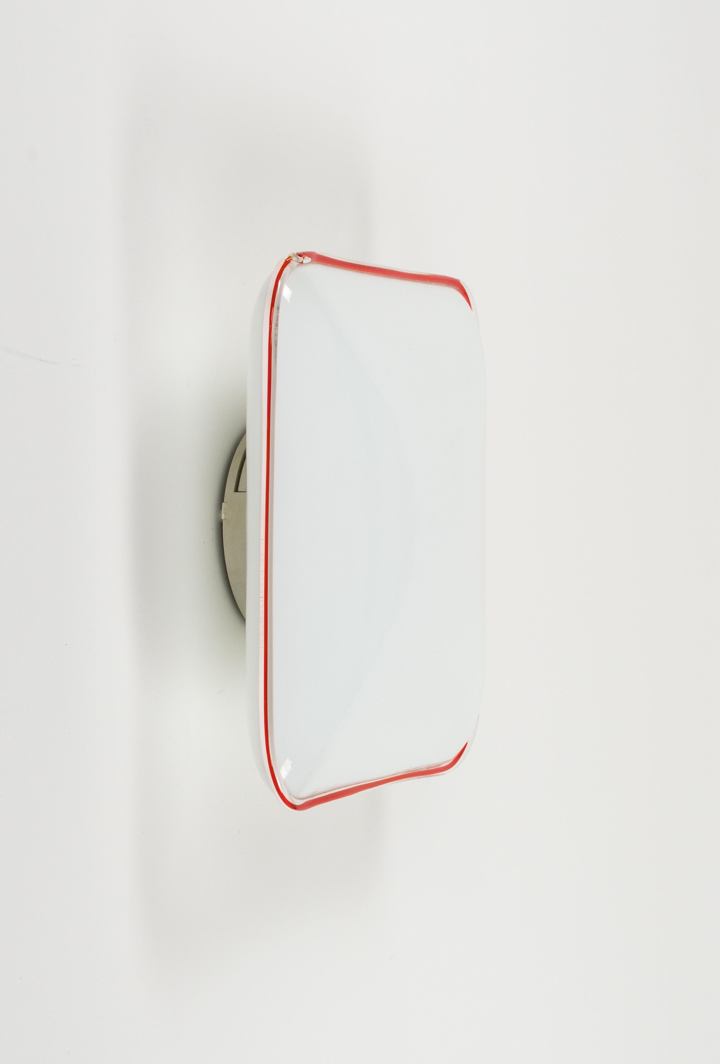 Plafonnier ou applique du milieu du siècle en verre Murano blanc avec une bordure en verre fusionné rouge et transparent par Leucos.

Fabriqué en Italie dans les années 1970.

Il utilise 2 ampoules. 

Le Label d'origine est encore attaché comme le