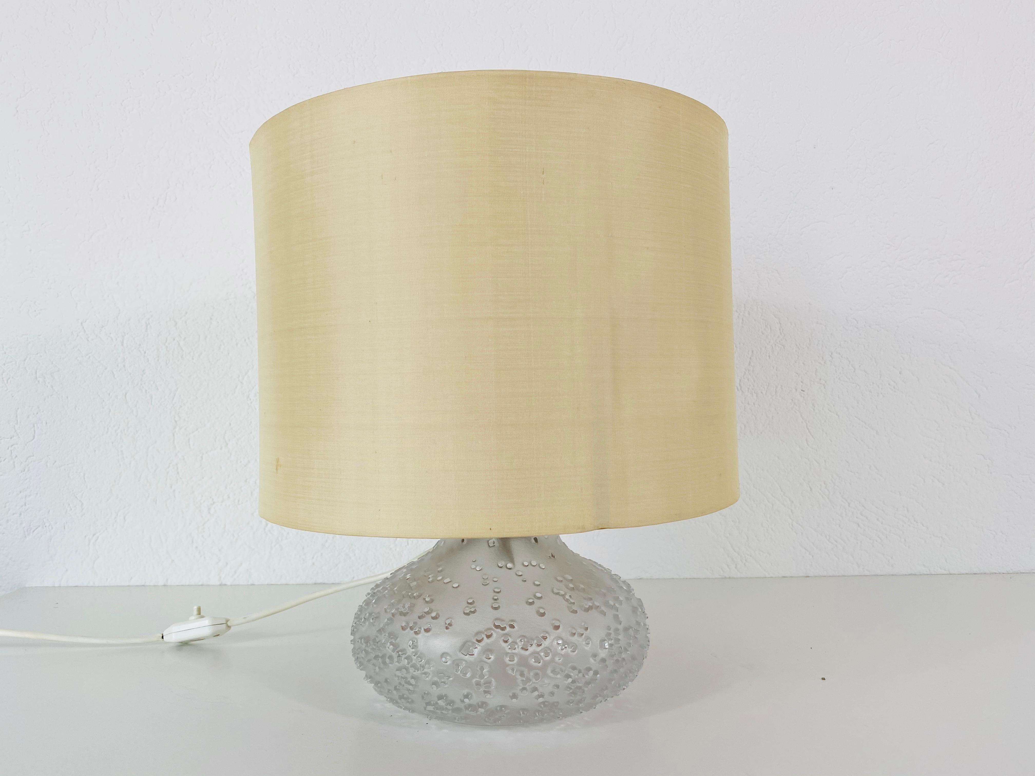 Una bellissima lampada da tavolo di grandi dimensioni realizzata negli anni '1960. La base è in vetro di Murano. Il paralume è di colore beige. La lampada da tavolo ha un bellissimo design italiano.

La lampada richiede una lampadina E27.