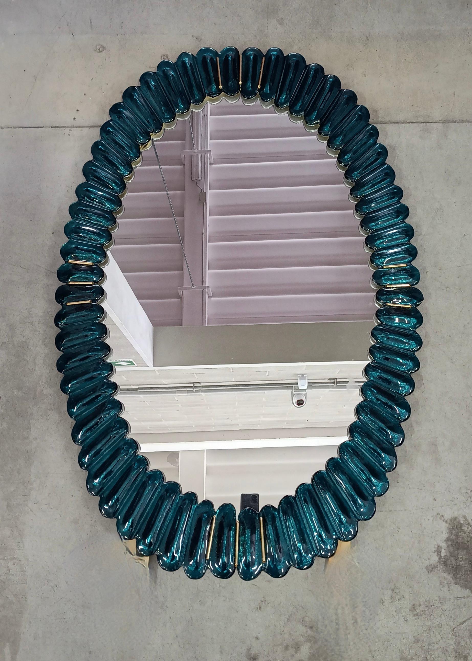 Stunning mirror in blazing aquamarine blue color Murano glass, Venice. A mirror that alone will furnish your home environment.

The mirror has a rear structure in wood, on which four Murano aquamarine blue glass sections are mounted to form an oval