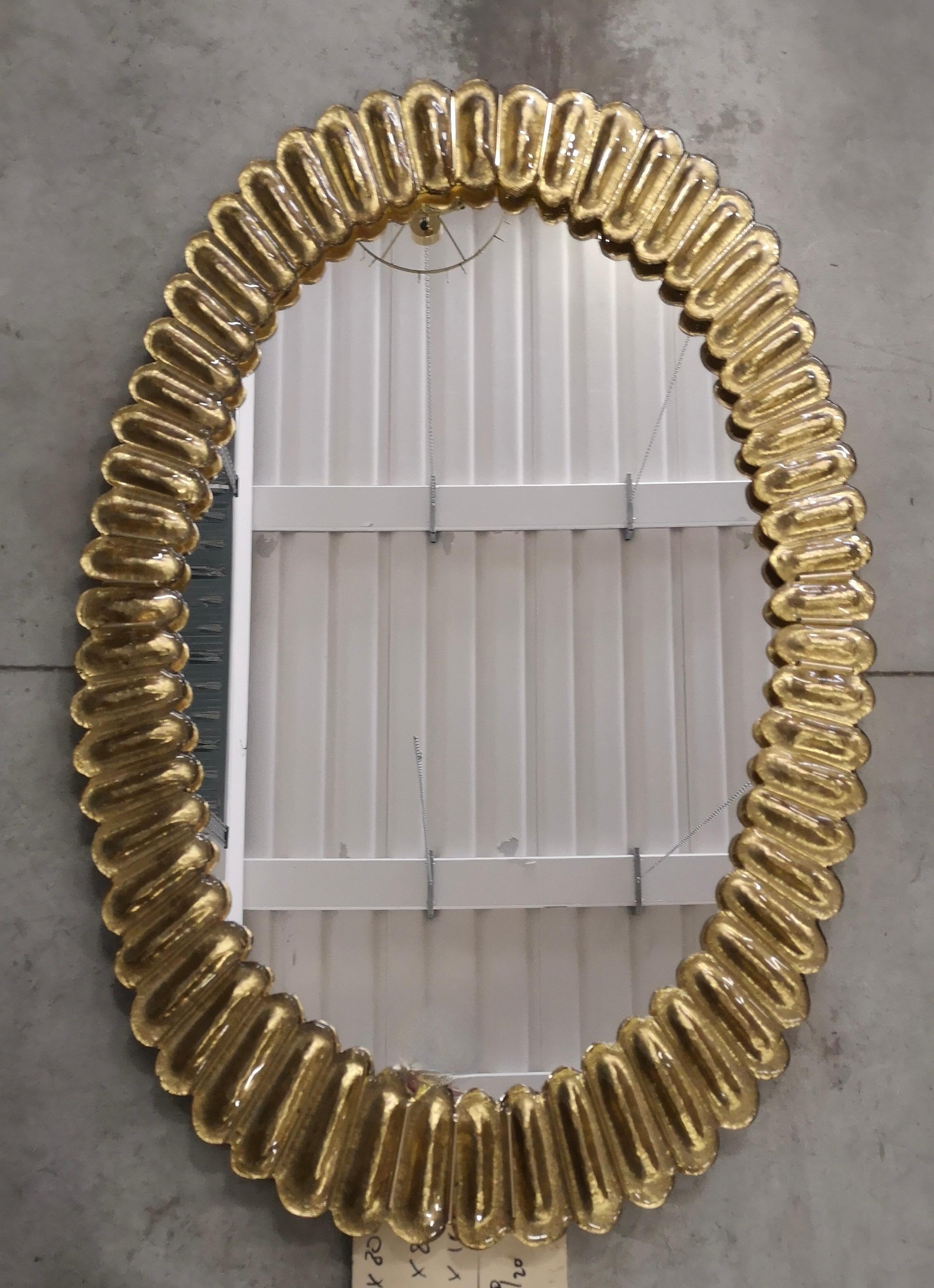 Wunderschöner Spiegel aus goldfarbenem Murano-Glas, Venedig. Ein Spiegel, der allein Ihr Zuhause einrichtet.

Der Spiegel hat eine Rückwand aus Holz, auf der vier goldene Murano-Glasscheiben montiert sind, die ein Oval bilden, wie auf dem Foto zu