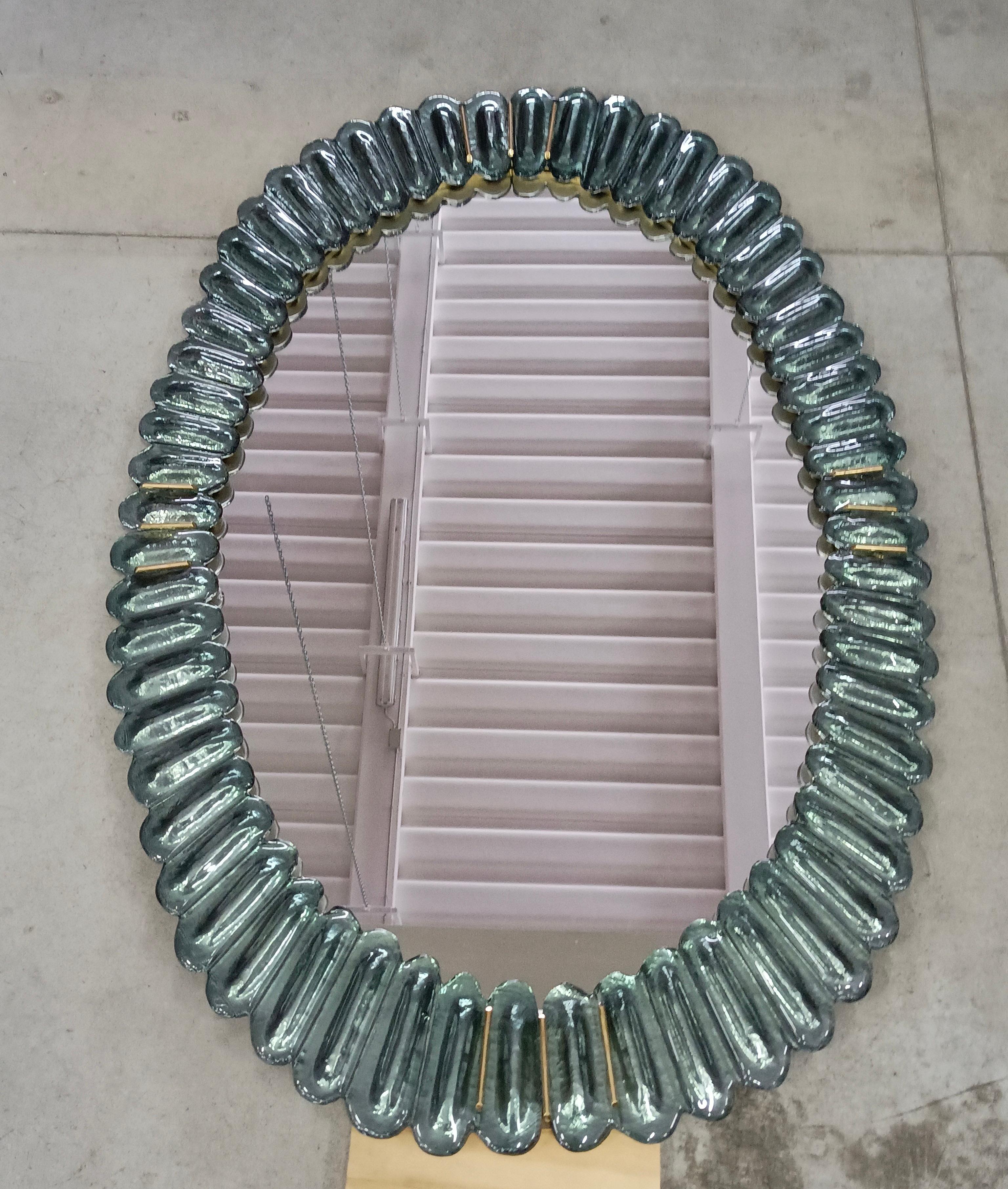 Superbe miroir en verre de Murano, Venise, de couleur vert aigue-marine flamboyant. Un miroir qui, à lui seul, meublera votre environnement domestique.

Le miroir a une structure arrière en bois, sur laquelle quatre sections de verre de Murano de