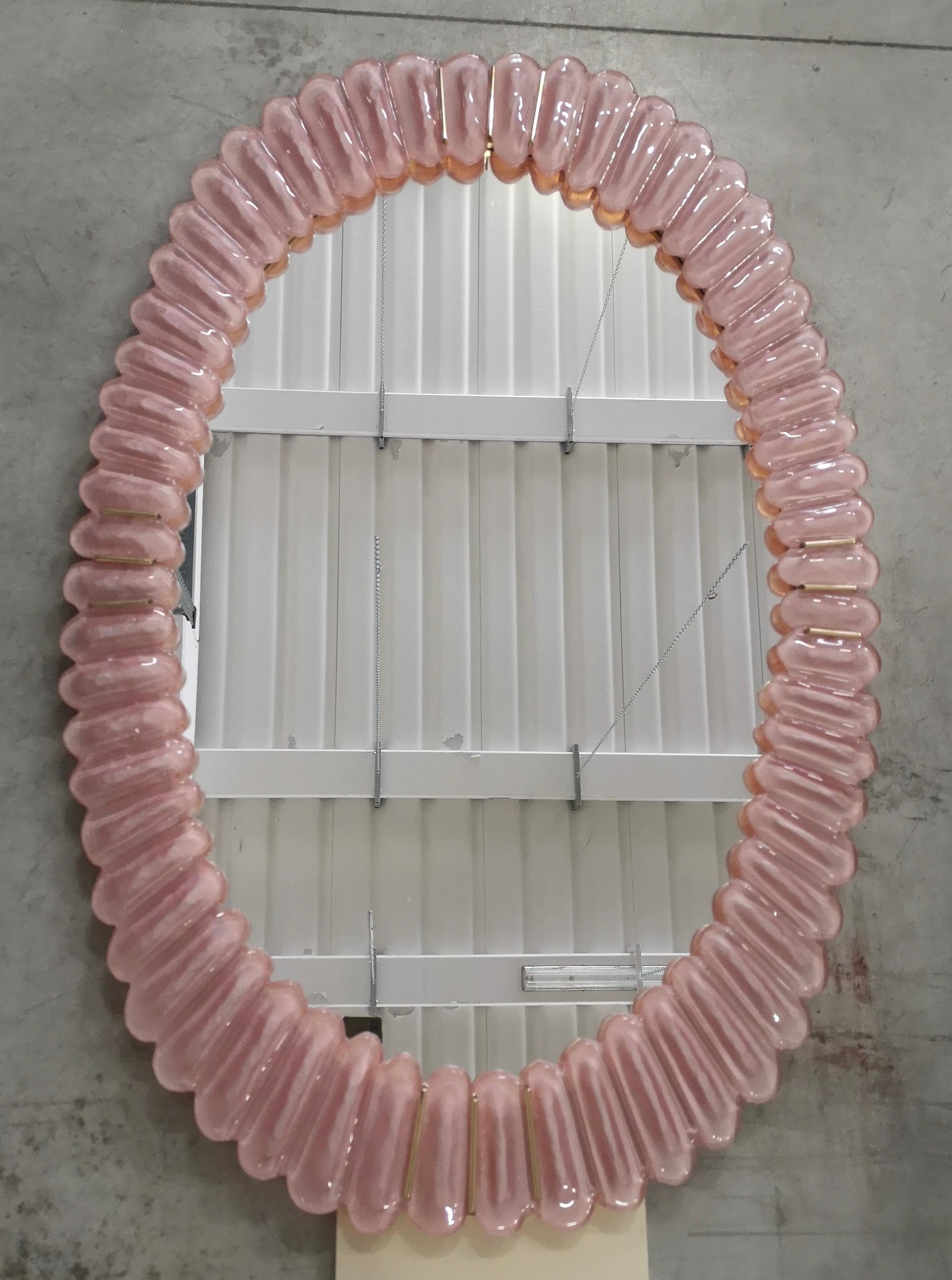 Stunning mirror in blazing pink color Murano glass, Venice. A mirror that alone will furnish your home environment.

The mirror has a rear structure in wood, on which four Murano pink glass sections are mounted to form an oval as in the photograph.