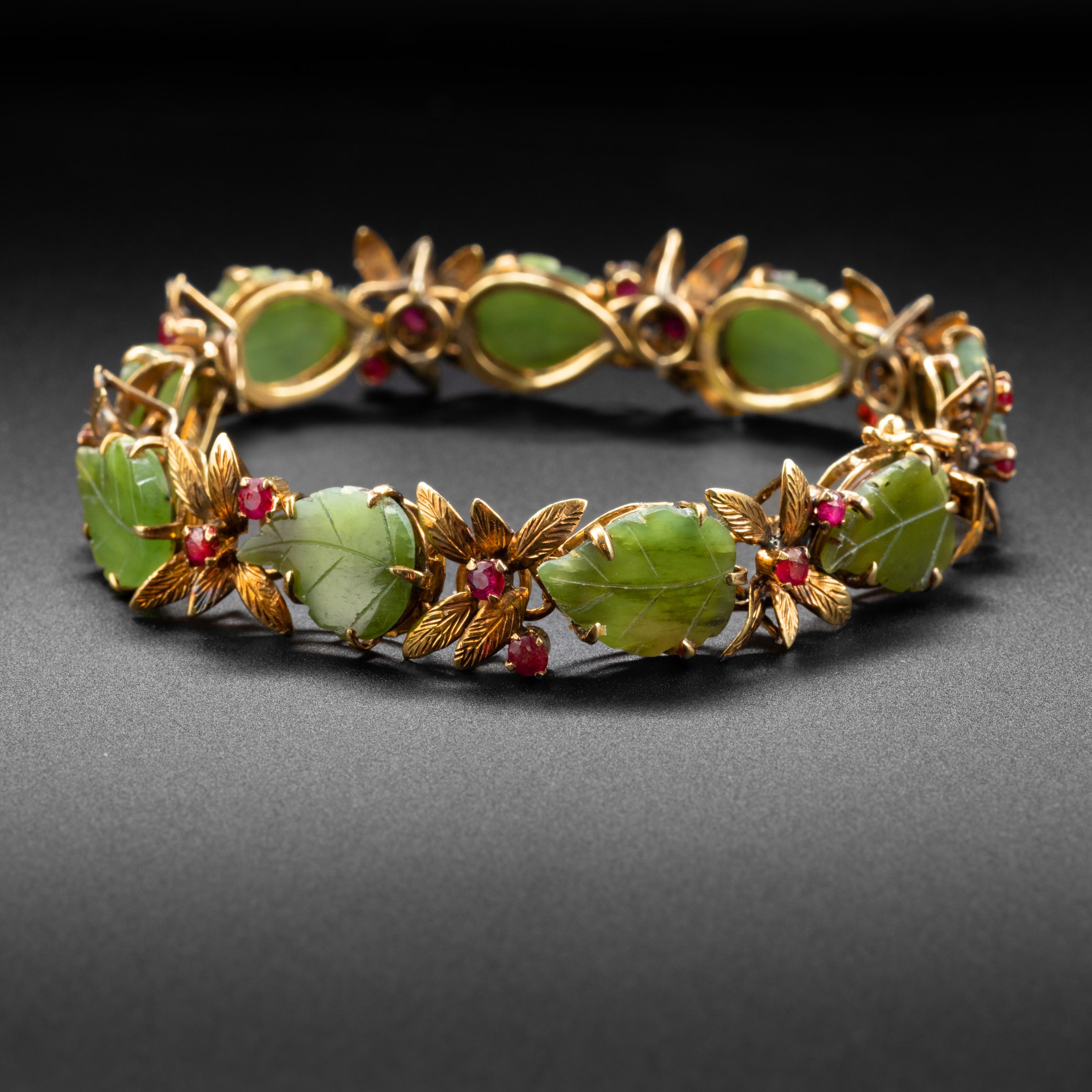 This one-of-a-kind bracelet from the late 1940s- early 1950s features leaves of translucent green natural and untreated nephrite jade nestled between long, slender leaves rendered in buttery 18K gold and set with vivid red natural ruby 