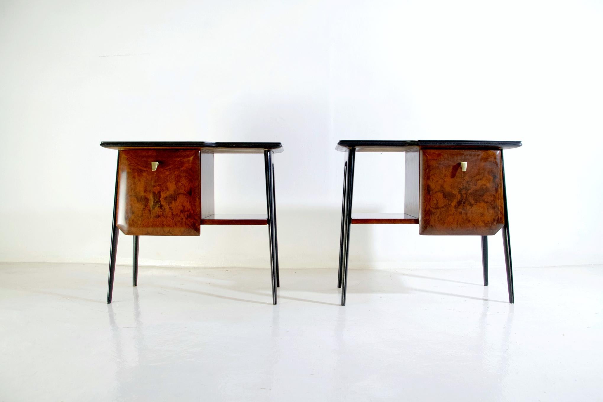 A pair of nightstands with a clean design in walnut burl wood, glass top and legs in blackened ash wood. Each nightstand has a small cabinet with a brass handle and an open shelf next to it. In excellent restored condition.
