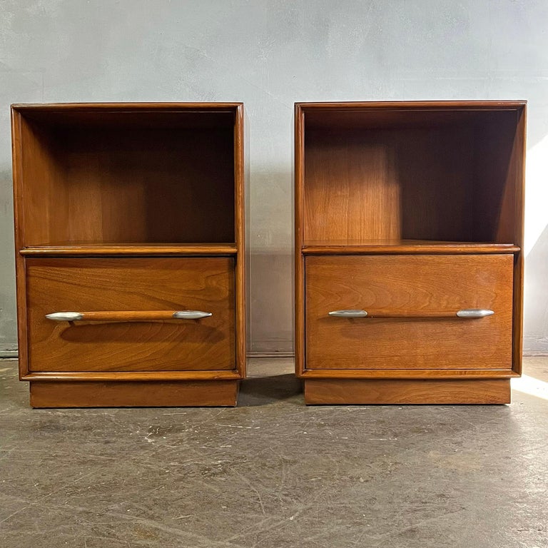 Beautiful and and elegant nightstands in walnut featuring an open compartment and pull out drawer with silvered handles. A classic design by one the most famous mid-century designers. 

Most photos taken outside in natural light.

In original