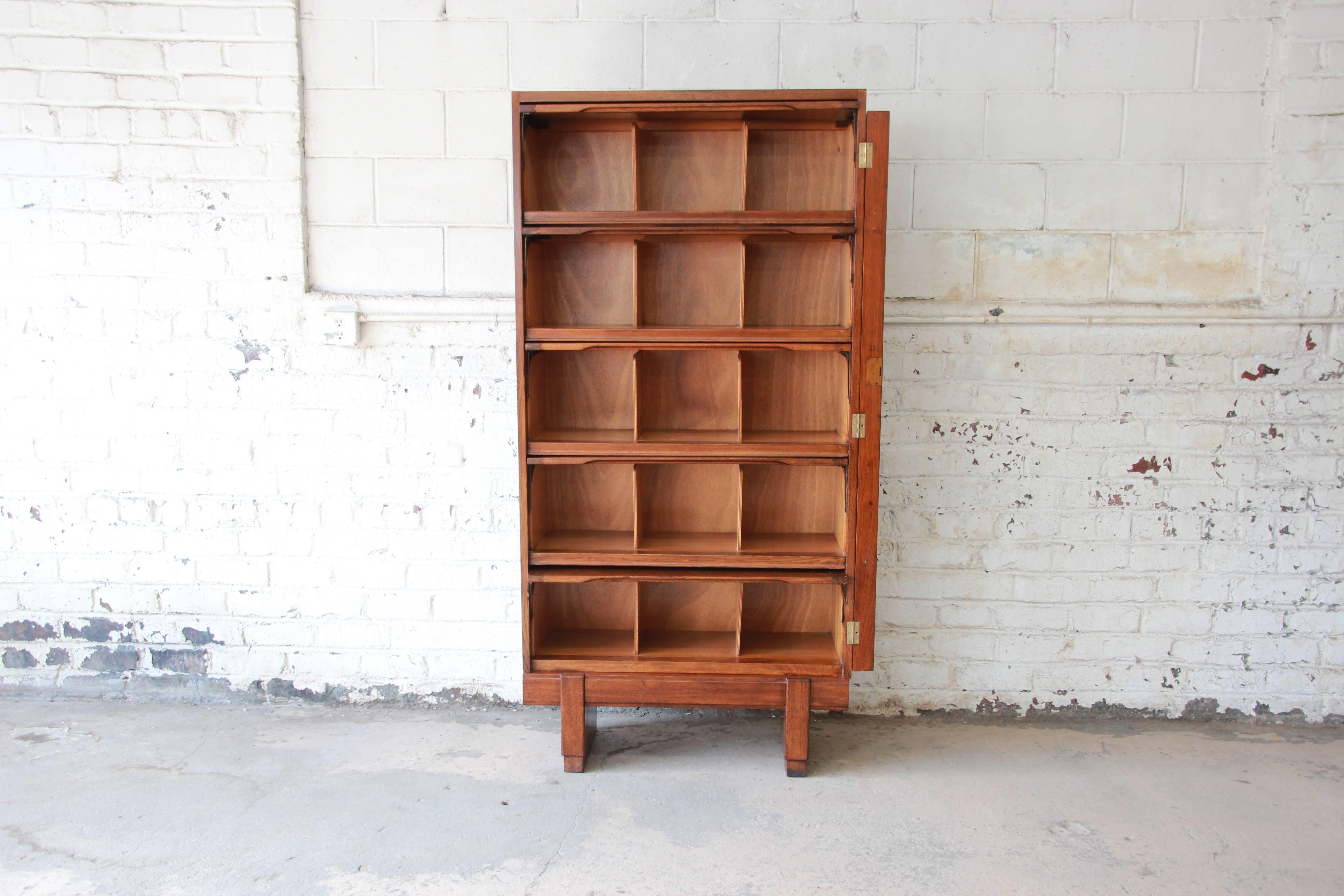 A very unique midcentury oak barrister bookcase. The bookcase features gorgeous oak wood grain and exposed dovetail joints. It offers ample room for storage, with five shelves, each with dividers. There is a unique locking mechanism that adds