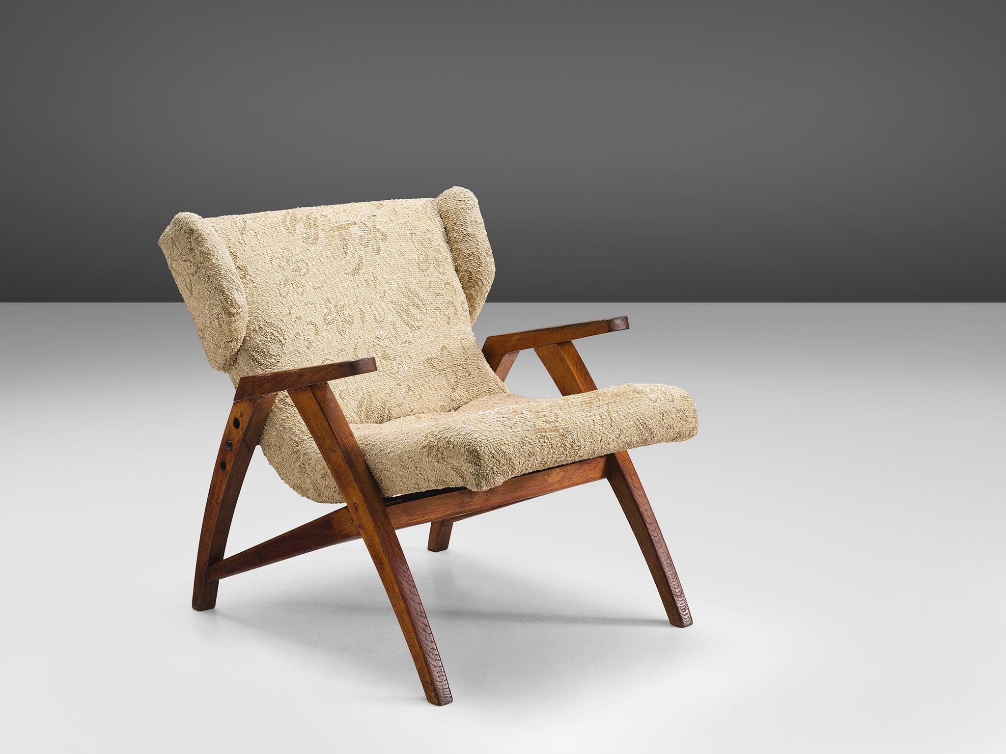 Easy chair, wood, beige brown fabric, oak, Czech Republic, 1940s.

This strong oak wingback chair is designed with a slightly sloped back in order to provide sitting comfort. The chair features small, geometric wings that are separated from the
