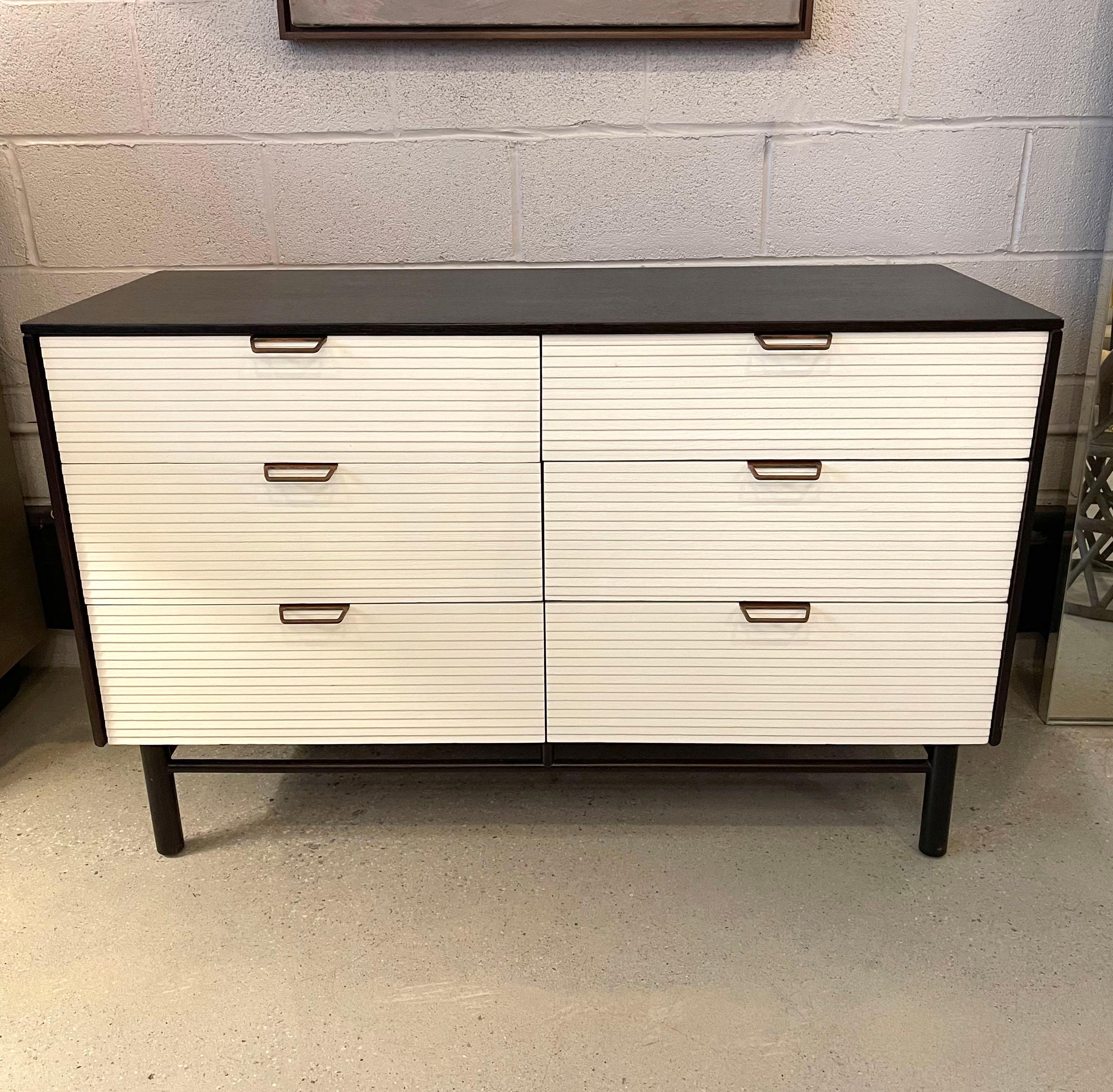 Mid-Century Modern, double-wide, oak, 6 drawer dresser by Raymond Loewy for Mengel Furniture Co. features an ebonized finish with contrasting white, louvered drawers with brass handles.