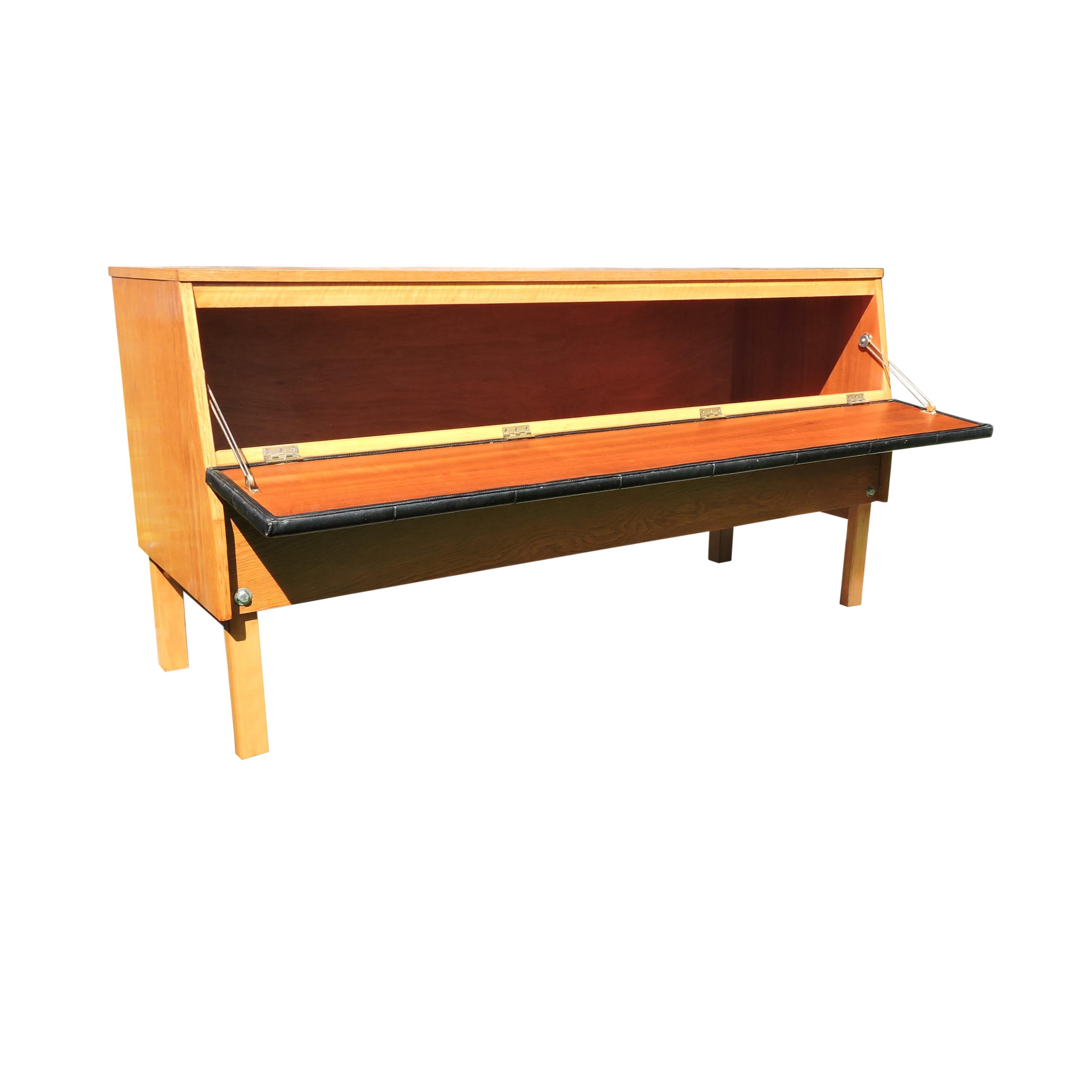 This G-Plan sideboard features a hinged upholstered drop front door leading to a hollow compartment for storage.
 