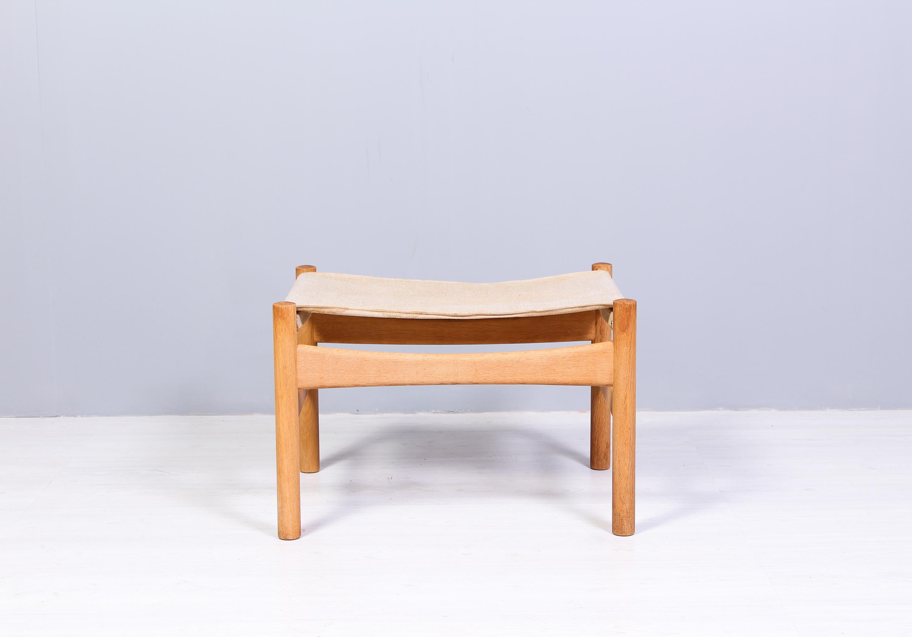 This oak stool is designed by Børge Mogensen and produced by Fredericia Stolefabrik in Denmark in the 1960s. The frame is made out of solid oak with a canvas upholstery. The frame is in good condition with signs of usage and patinas, the canvas have