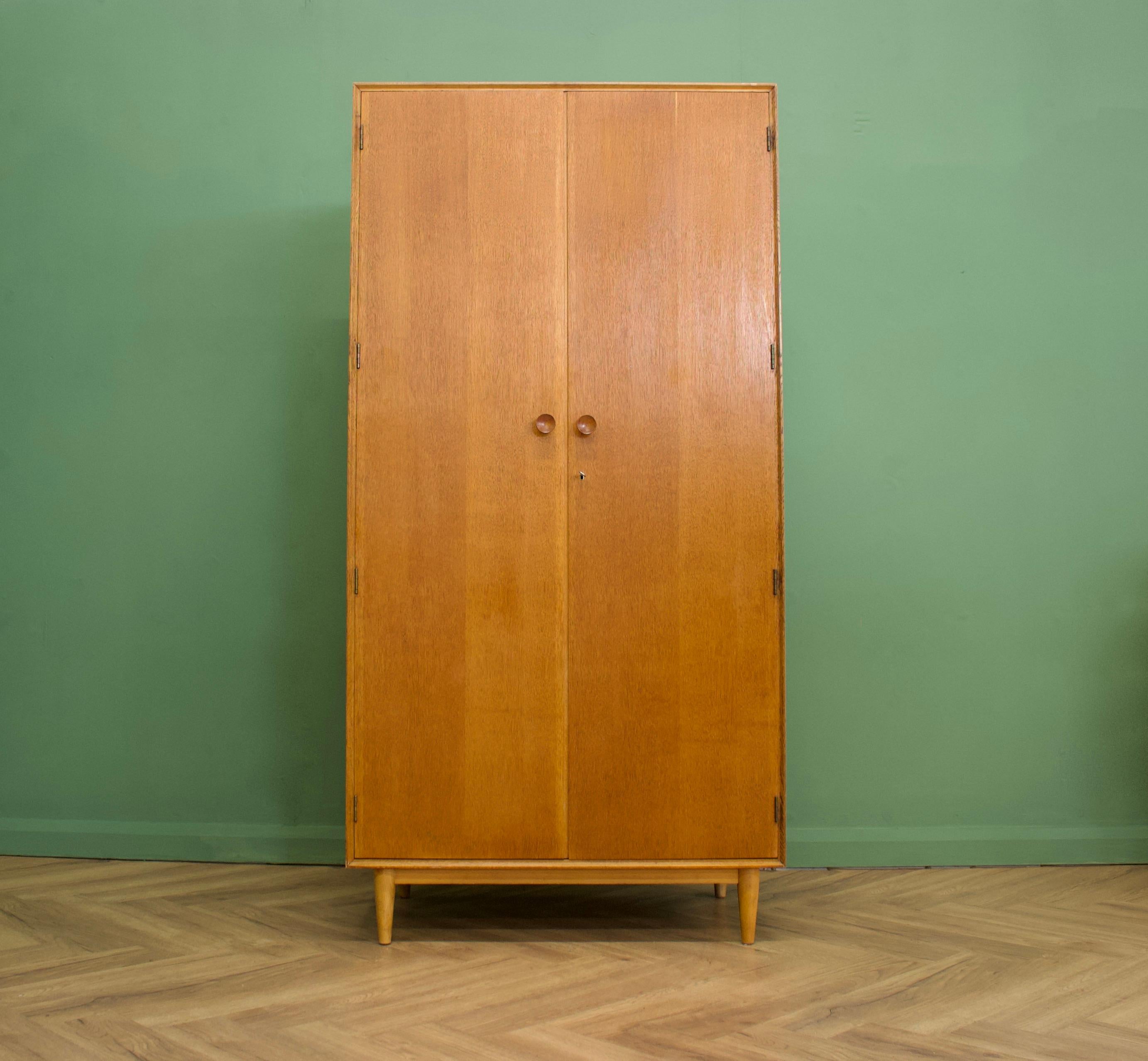Midcentury wardrobe
Manufactured in the UK by Meredew
Made from oak and oak veneer.

Featuring solid oak handles two rails and a two adjustable and removable shelves.