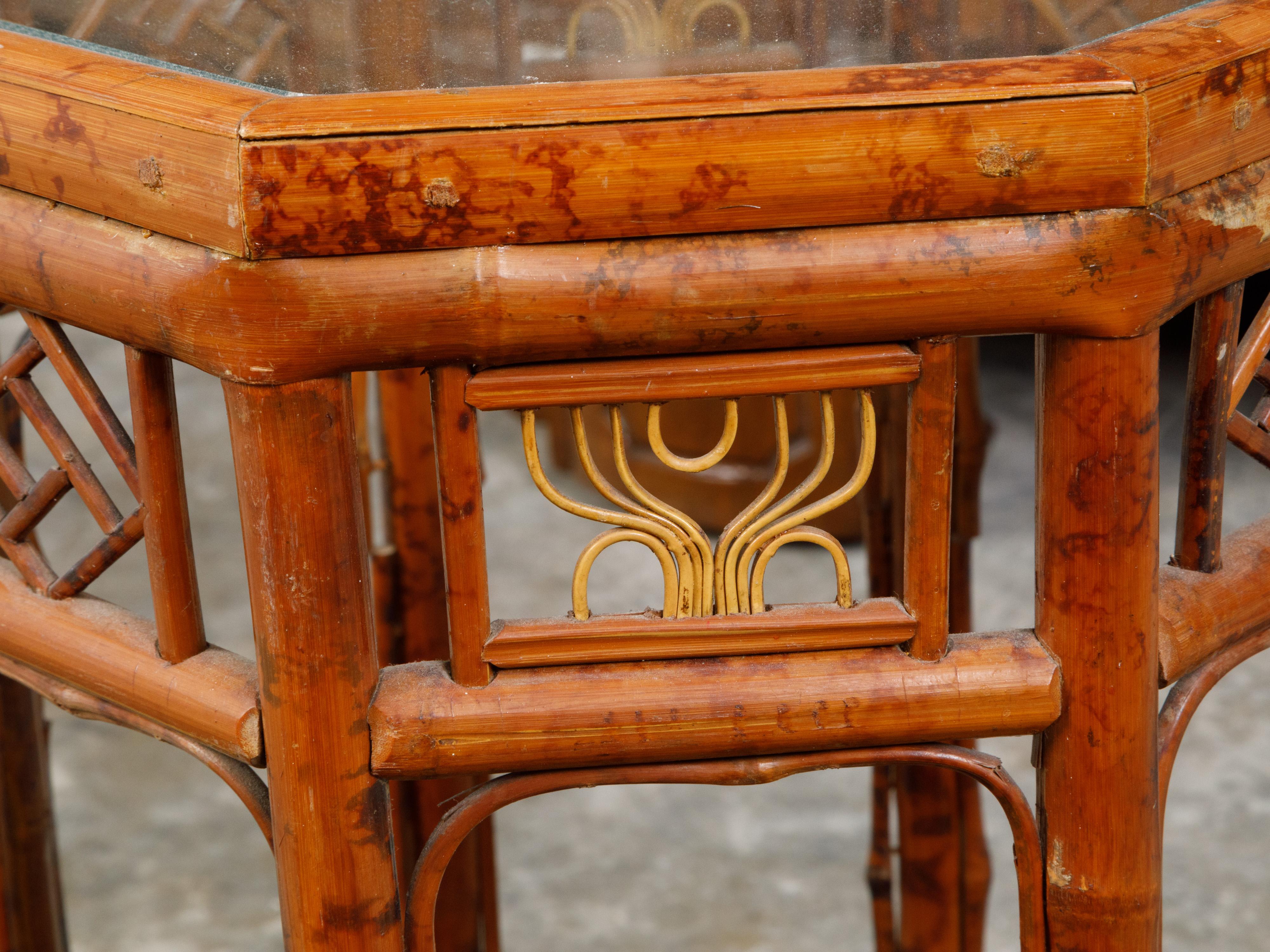 A bamboo octagonal side table from the mid 20th century, with glass top and geometric motifs. Created during the midcentury period, this side table features an octagonal glass top sitting above a bamboo structure. Accented with geometric motifs on