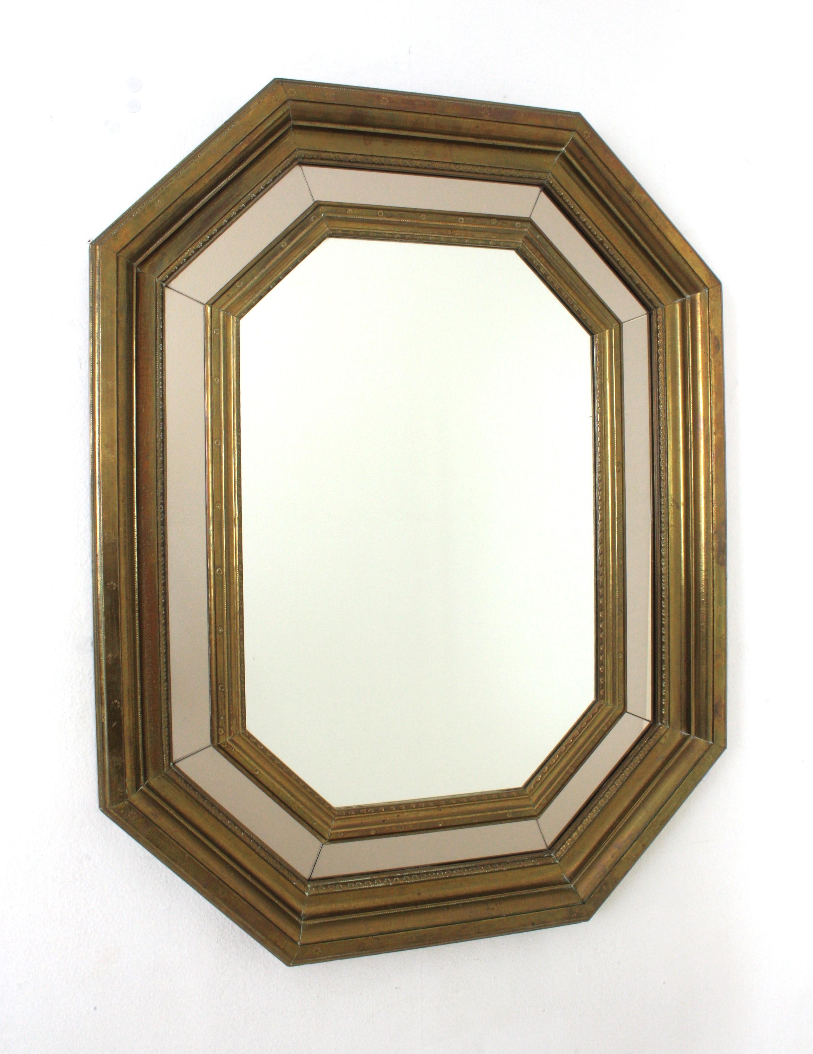 Elegante specchio ottagonale Hollywood Regency con cornice in ottone e specchio fumé. Spagna, anni '60.
Questo specchio glamour presenta strati di ottone e uno specchio in vetro fumé che circondano uno specchio centrale. Forma ottagonale.
Uno strato