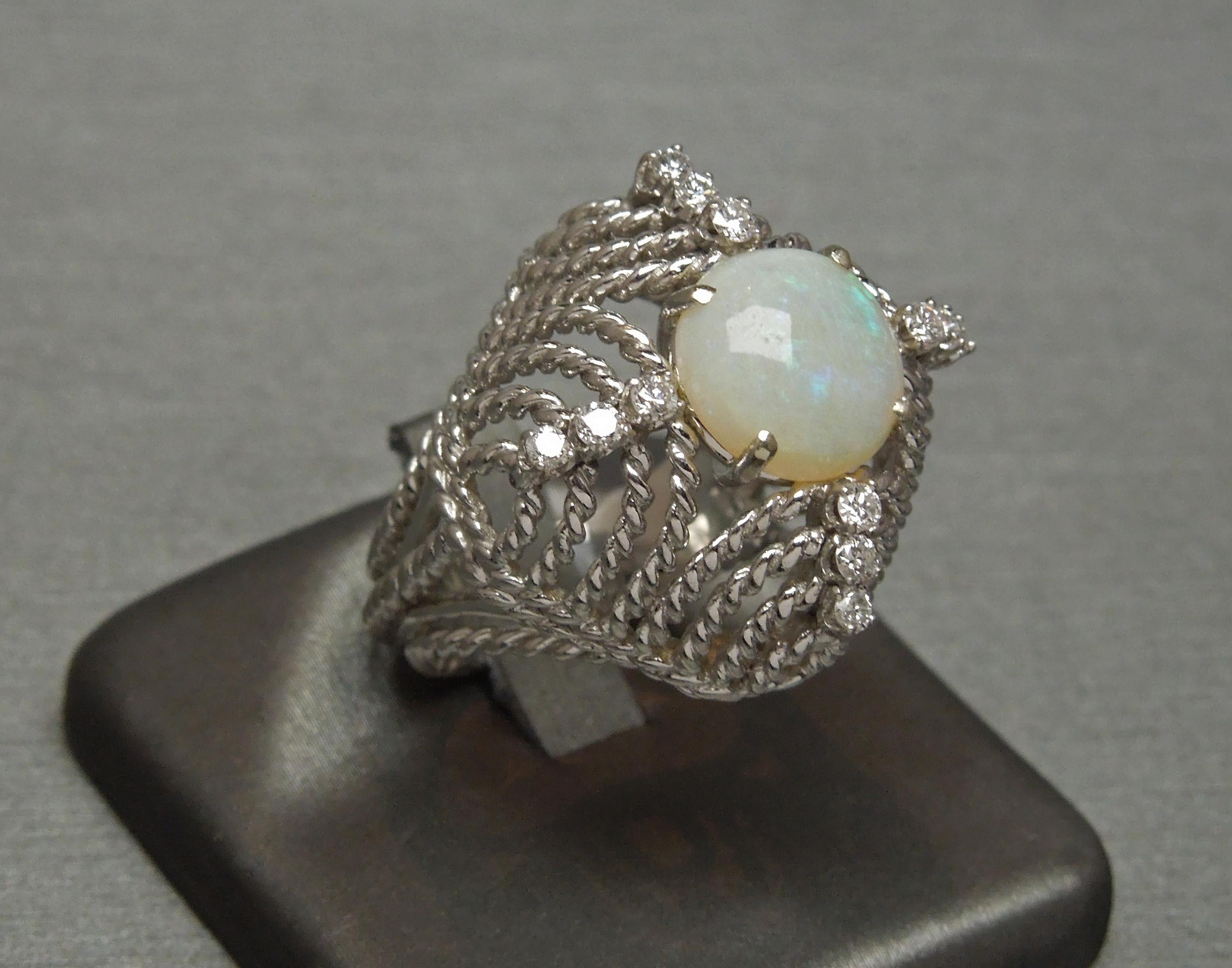 This Midcentury Opal Dome Ring features a central Round Australian Fire Opal at 9.5mm in diameter, secured in a 4-Prong setting. Opal, along with Tourmaline is the birthstone for those born in the month of October. Accented with 12 Colorless Nearly