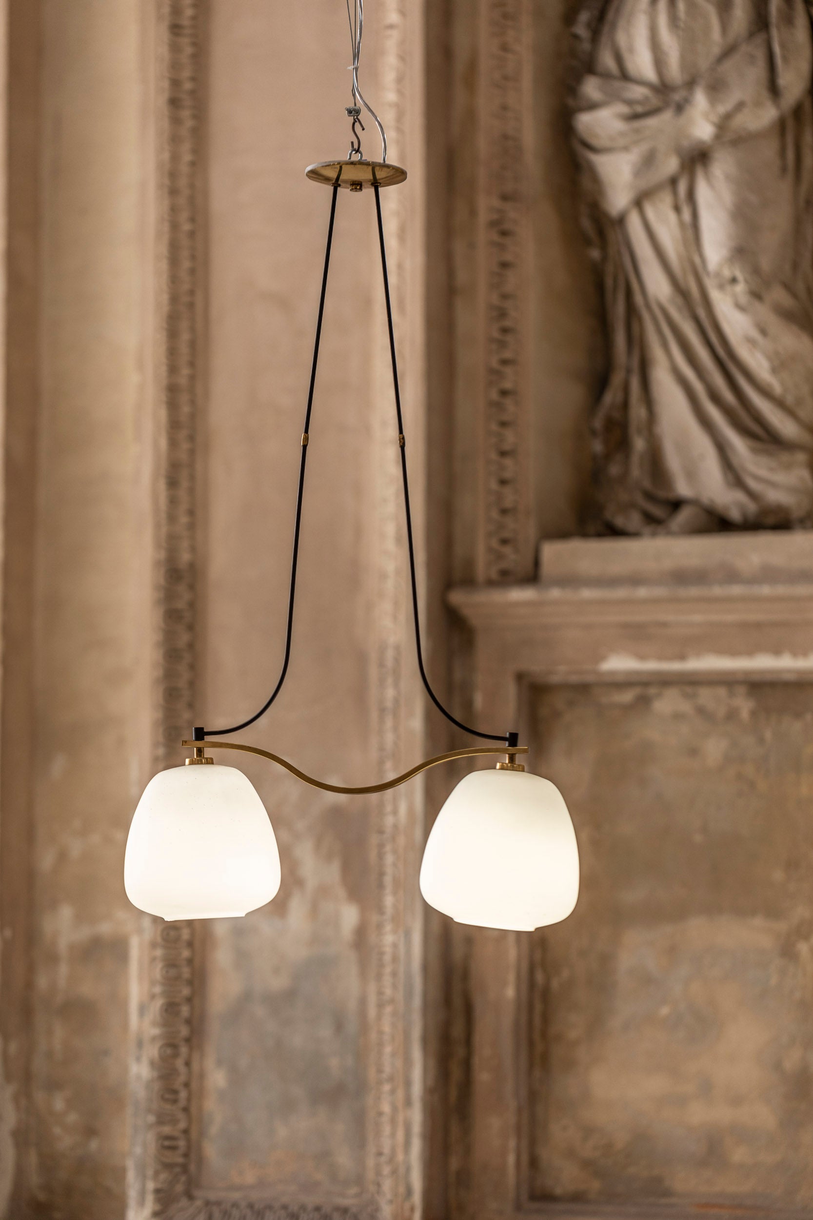 Elegant lustre avec une fine structure en laiton doré, deux lumières en verre opalin, finement décorées. 
Fabriqué en Italie dans les années 50.
