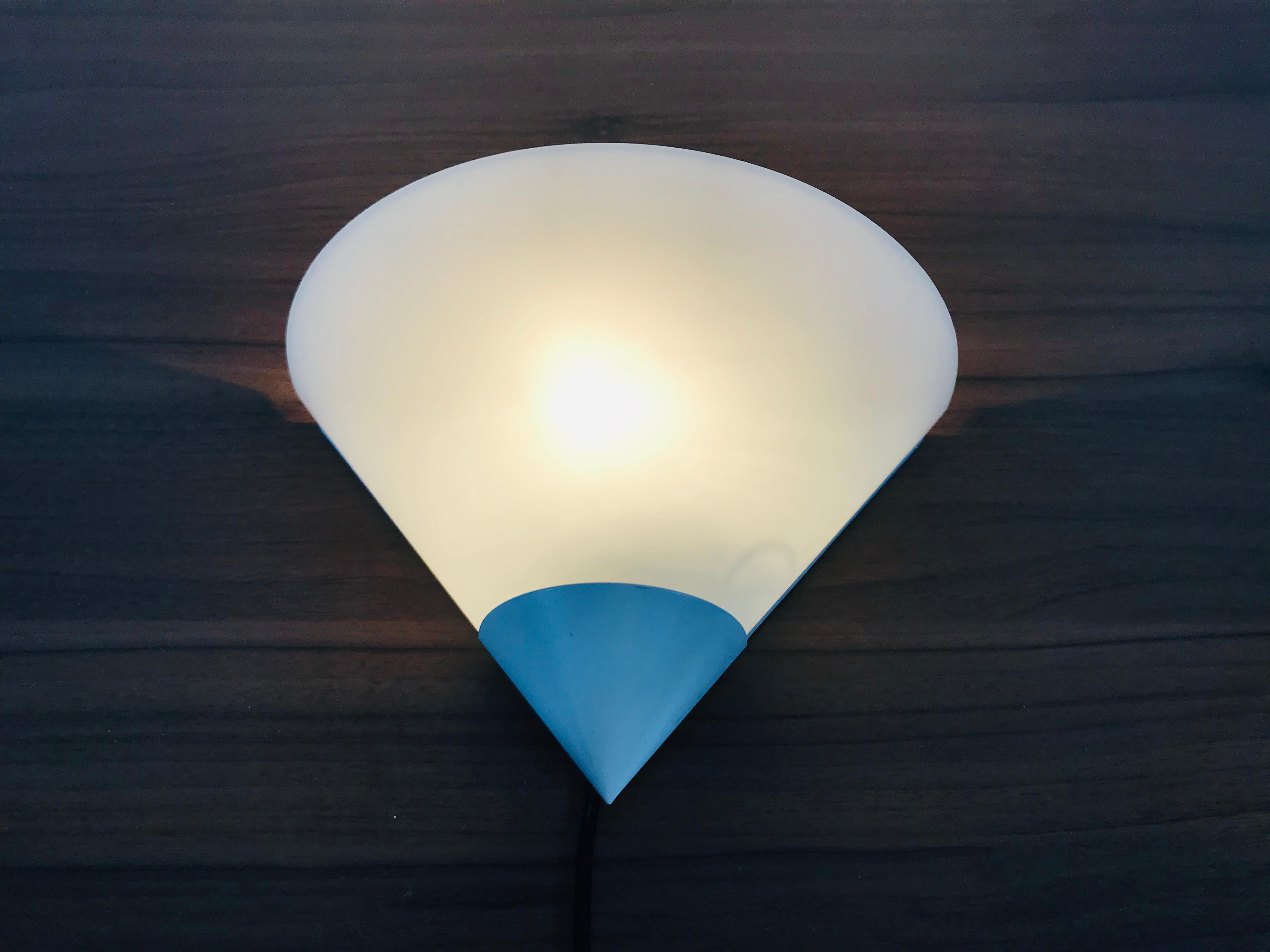 A beautiful Mid-Century Modern wall lamp by Glashütte Limburg made in Germany in the 1970s. It has a beautiful triangle shape and is made of aluminium and opaline glass. The back is white metal.

The light requires one E14 light bulb.