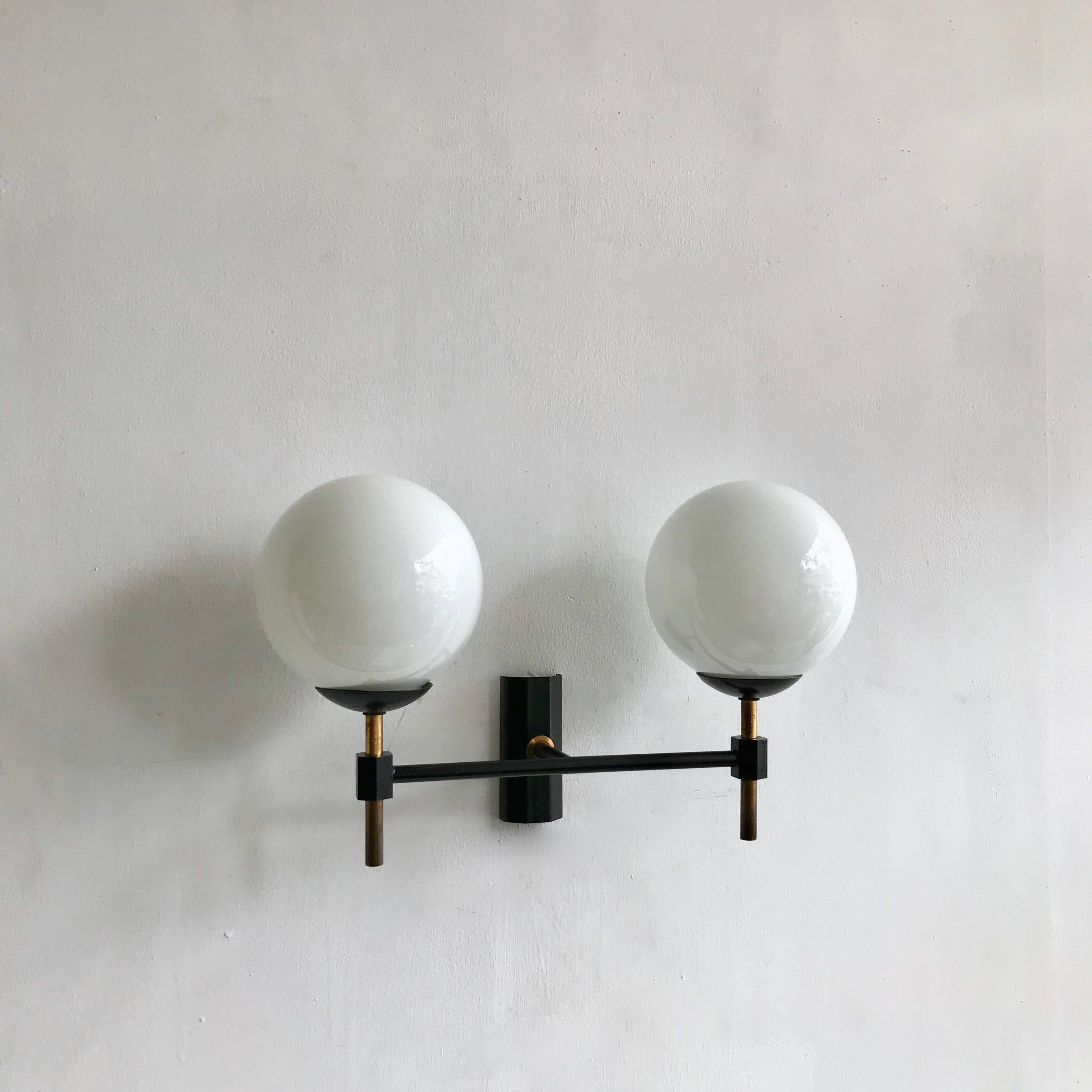 Stylish midcentury opaline wall light made from brass with original black paint finish. The wall light has great proportions. With two thick polished glass opaline globe shades. The wall light takes two B15 lamps.

The wall light has been fully