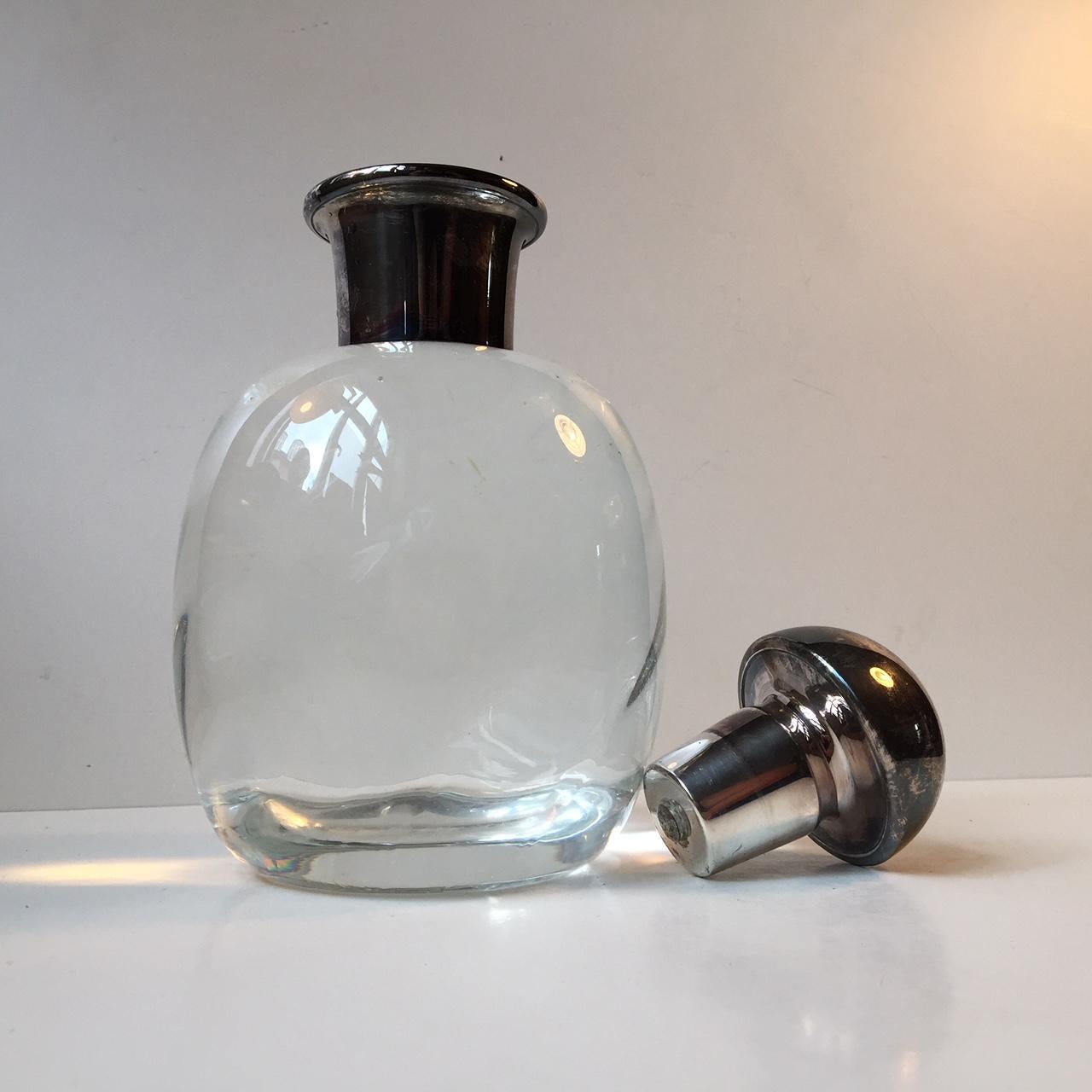 Egg shaped heavy and thick crystal decanter from Strömbergshyttan in Sweden. It was designed and manufactured during the 1940s or 1950s. It has a silver collar and stopper. Capacity 1 liter.