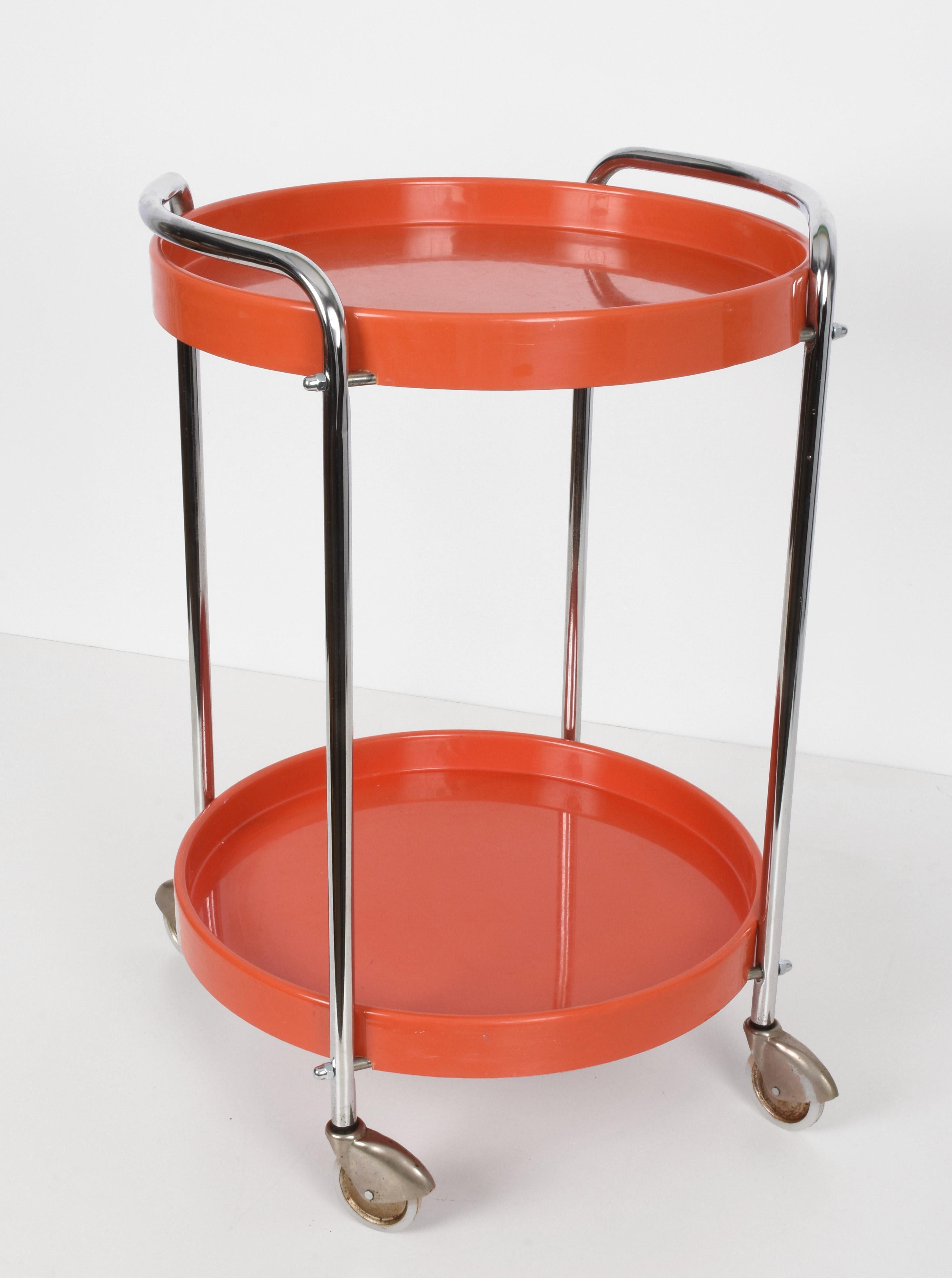 Very rare midcentury orange plastic and metal chrome round bar cart. This unique piece was produced in Italy during the 1950s.

This item is in very good vintage conditions and has two round plastic shelves, a metal chrome structure and four