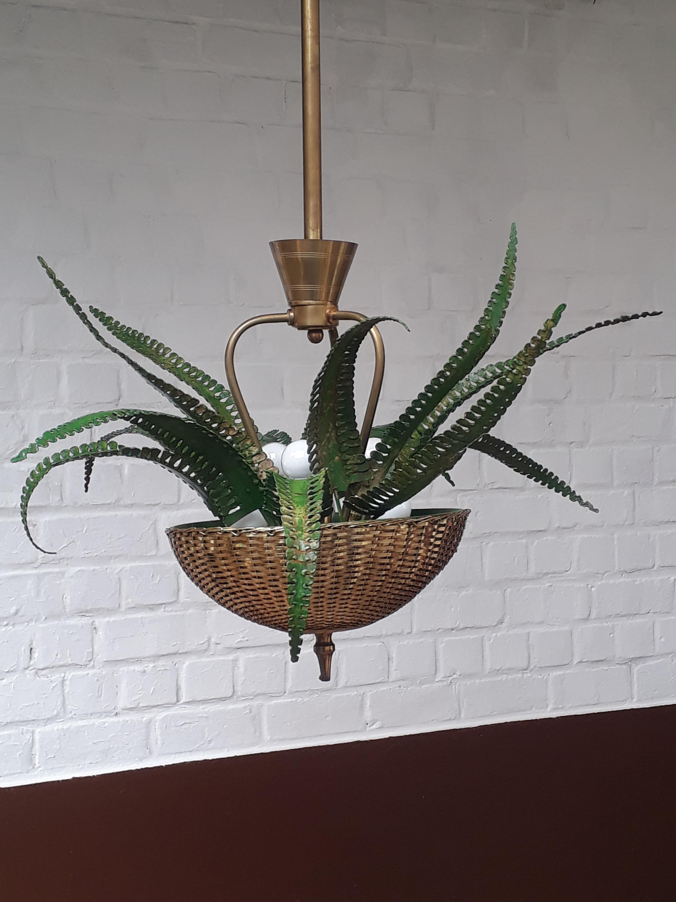 Dating from the mid-1950s, this eye-catching chandelier is quite unique with an organic fern type decor growing out of a woven brass filament basket. It has an interesting “living” type patina applied directly to the leaves.