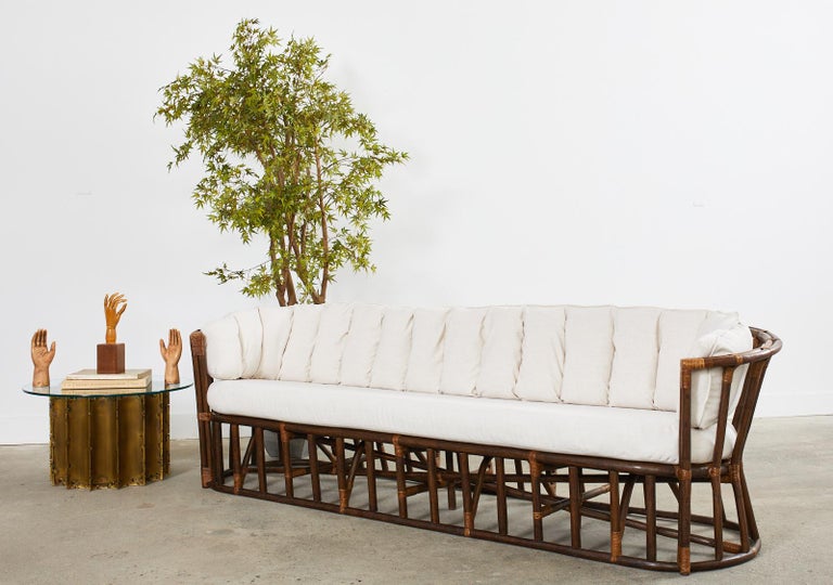 Divine midcentury organic modern bamboo rattan sofa or settee with demilune or crescent shaped ends. The bentwood rattan frame features a channel back conforming seat cushion with new linen style fabric. Constructed with excellent joinery and