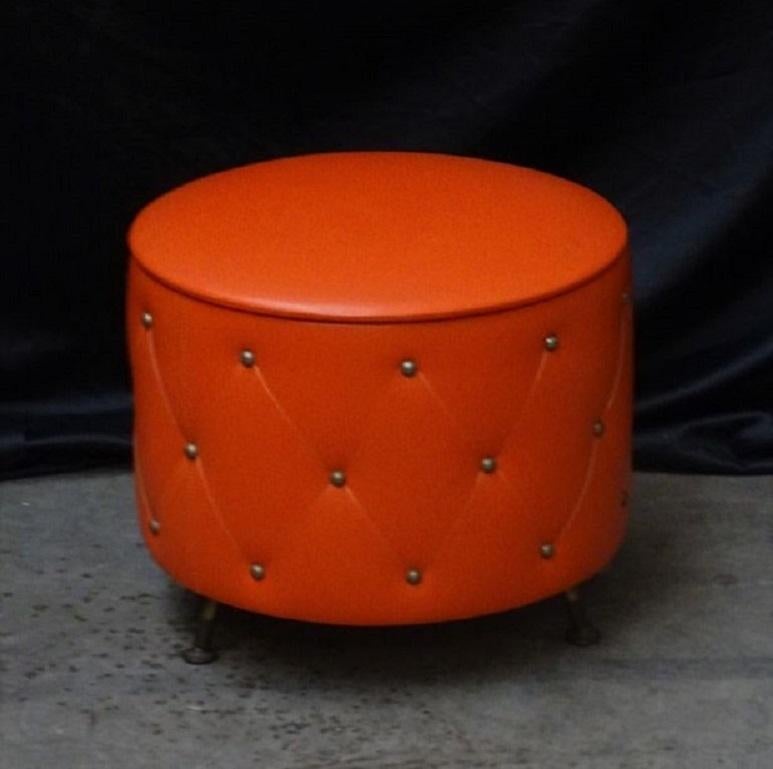 Striking 1960s ottoman stool in excellent condition. Mid-Century Modern multifunctional stool with a removable top offering useful storage inside. Tightly stretched orange vinyl upholstery with copper rivets on three solid brass vivier legs. This