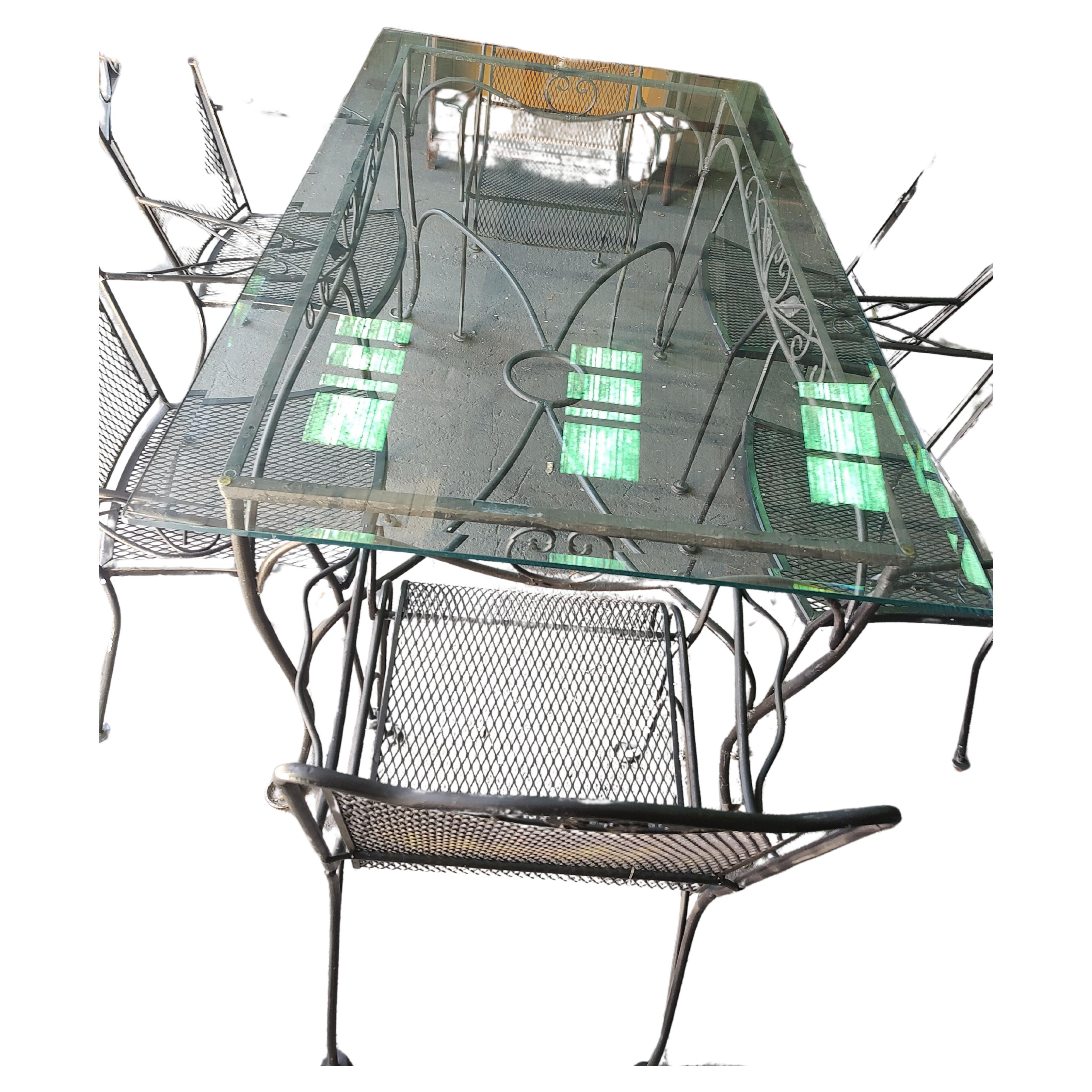 Favoloso set di 8 pezzi composto da un grande tavolo da pranzo dei primi anni '50, in ferro pesante decorato con un grande piano in vetro smussato. 6 poltrone della fine degli anni '60 con sedili in rete per una facile manutenzione. Set da veranda