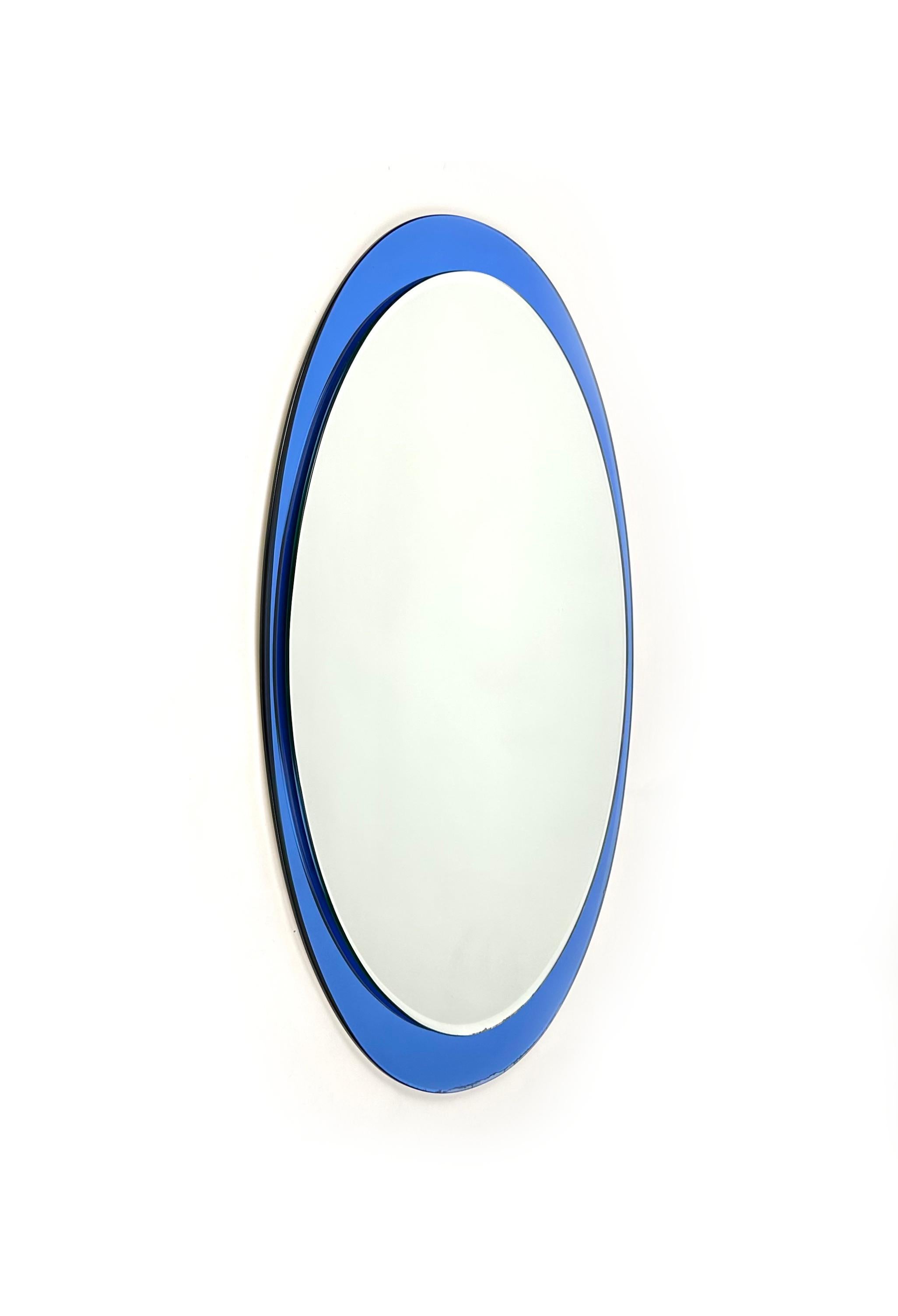 Midcentury oval wall mirror with blue mirror frame and double decreasing beveled by Metalvetro Galvorame. 

Made in Italy in the 1970s. 

It comes with its original label signed 