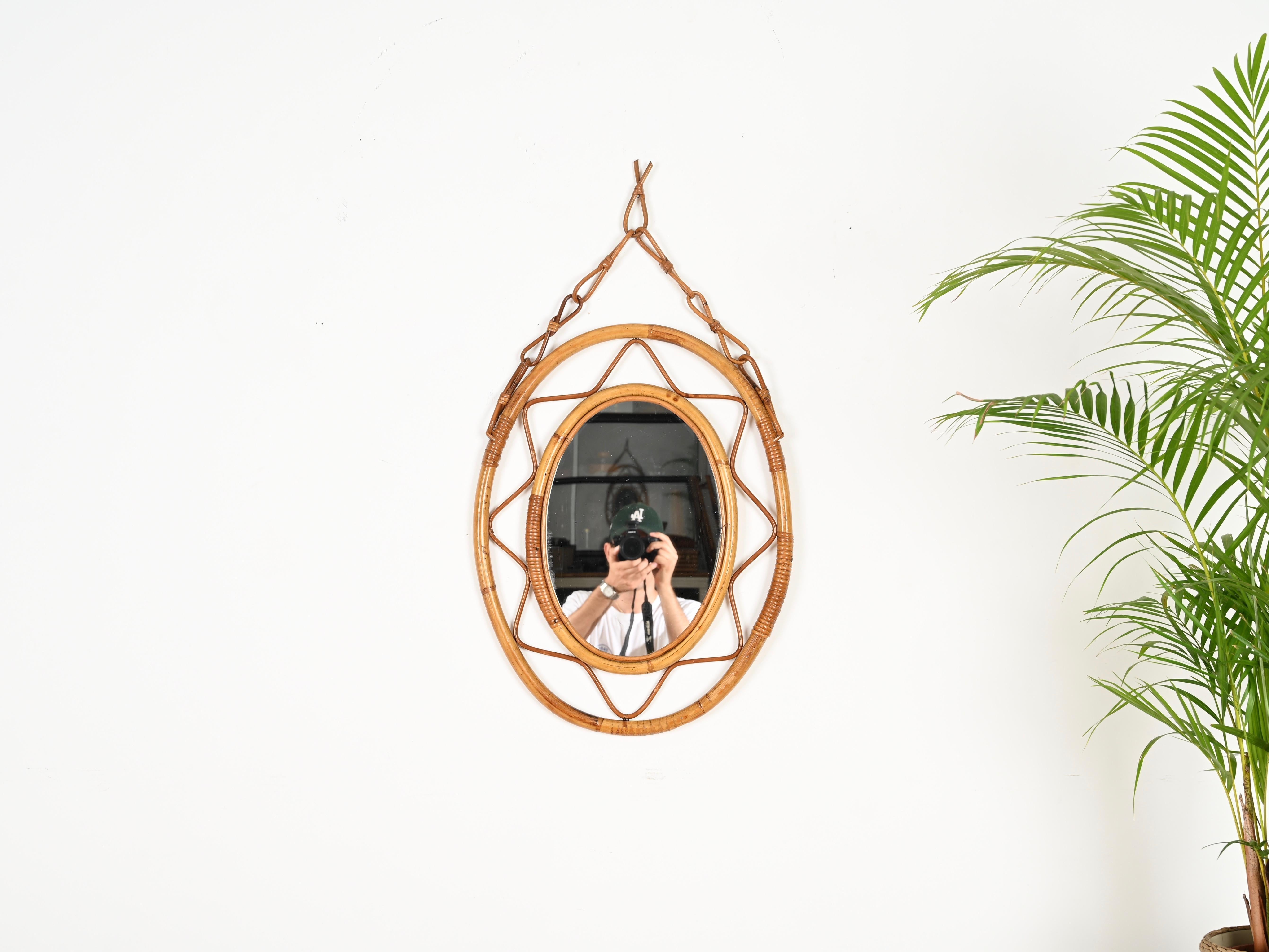 Splendido specchio ovale in stile Costa Azzurra di metà secolo con catena completamente realizzato in bambù, rattan e vimini intrecciato. Questo delizioso specchio organico è stato realizzato a mano in Italia negli anni Sessanta. 

Lo specchio ha