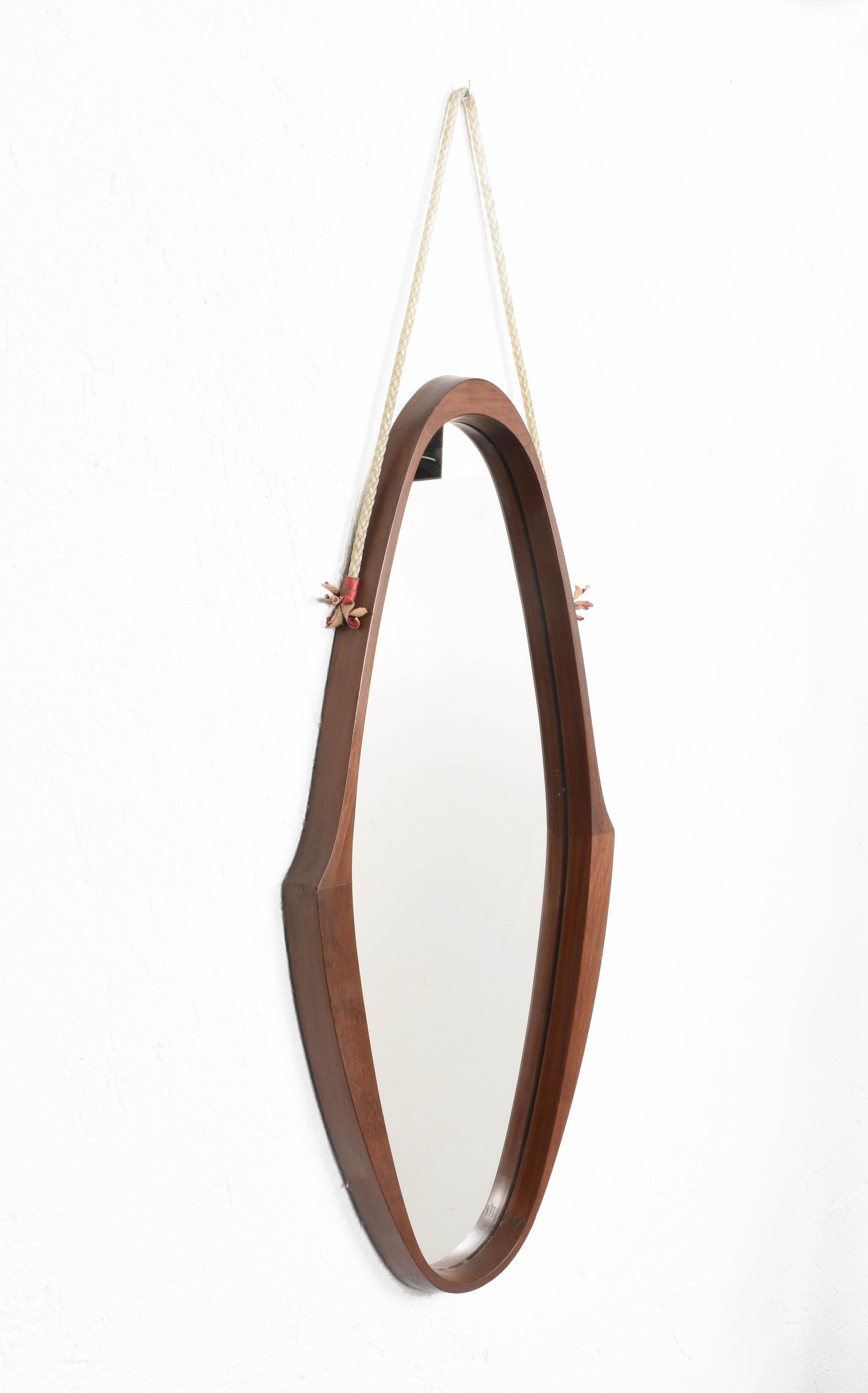 Amazing midcentury teak, nylon rope and leather oval wall framed mirror. This wonderful piece was produced in Italy during the 1960s.

This item has an astonishing teak oval structure with a unique design, the structure seems floating thanks to