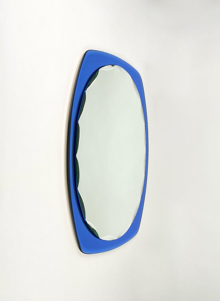 Oval wall blue framed mirror attributed to the Italian brand Cristal Art, 1960s.

In its essential and pure mid-century design and lines, this marvellous item features an carved oval mirror embedded into a fantastic deep sea blue mirror frame.