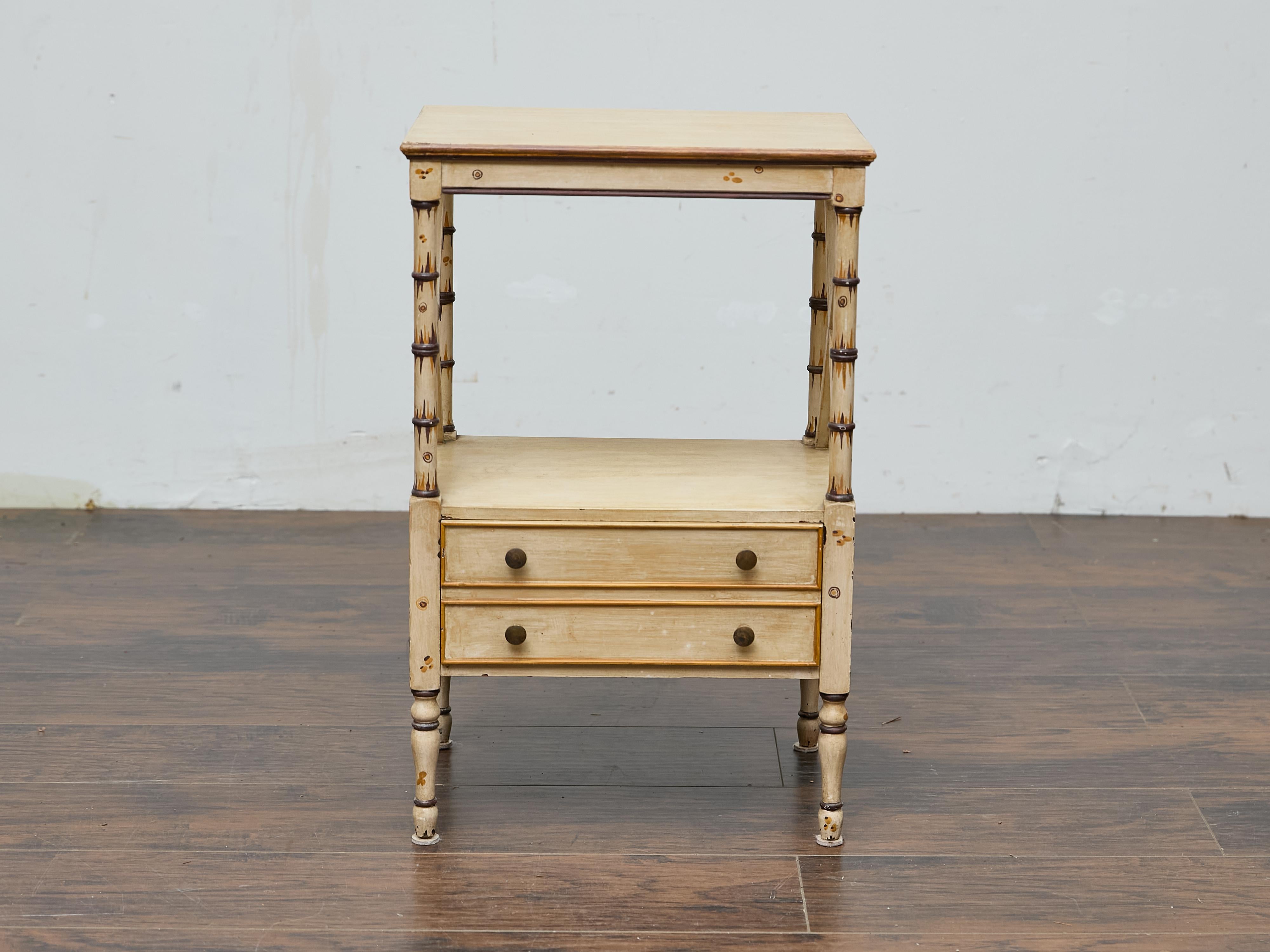 An English cream painted faux bamboo Midcentury side table. A charming blend of midcentury craftsmanship and timeless elegance, this English painted side table features a refined silhouette accentuated by faux bamboo details. The soft, cream-colored