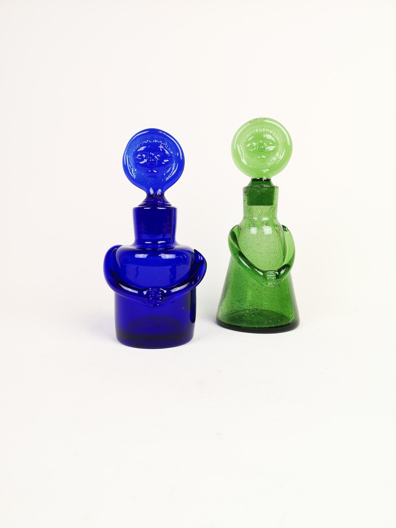 These bottles were made at Boda and designed by Erik Höglund in Sweden, 1960s.
They are both made in an artistic funny way, with that wonderful color signature from Höglund. 

Very good condition.

Measures: Green H 21, D 9 cm. Blue H 19, D