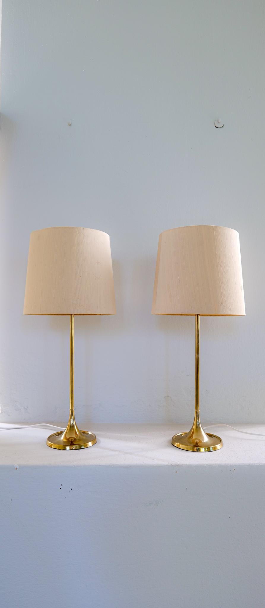 The small table version of the iconic Bergboms design. Cast iron base finished in brass. This pair of table lamps will give that great look to a vintage home or a twist to the modern home. This pair with original shades.

Good vintage working