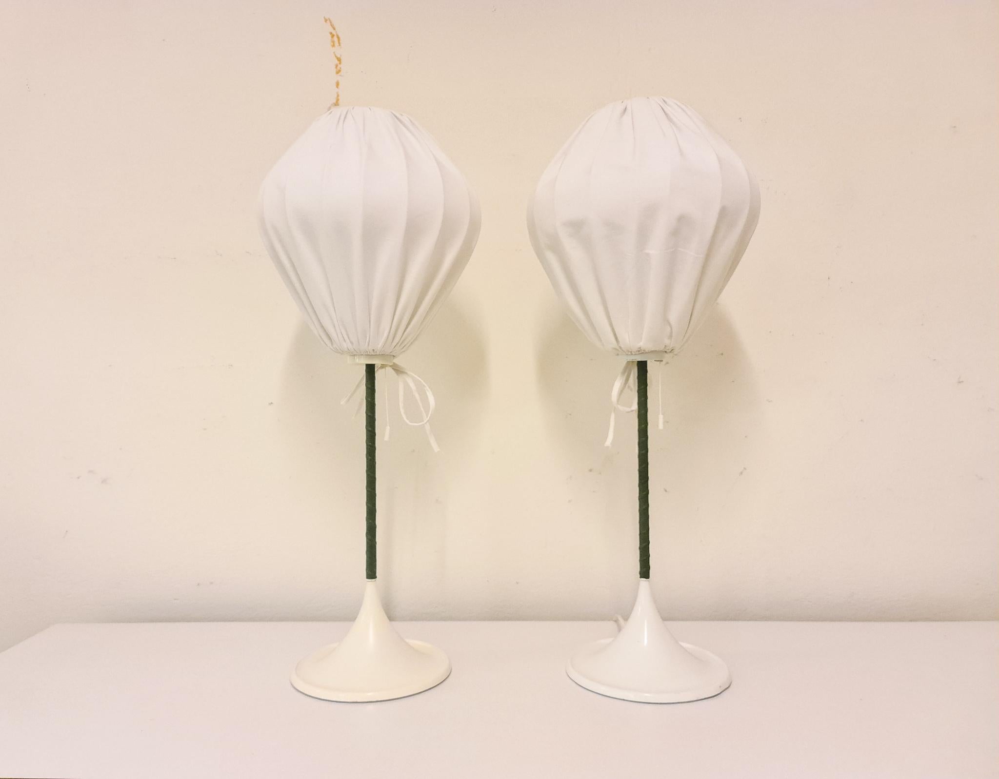 The table version of the iconic Bergboms design. Cast iron base finished with white lacquer. This pair of table lamps will give that great look to a vintage home or a twist to the modern home. The shade has a new fabric and its rod is in dark green