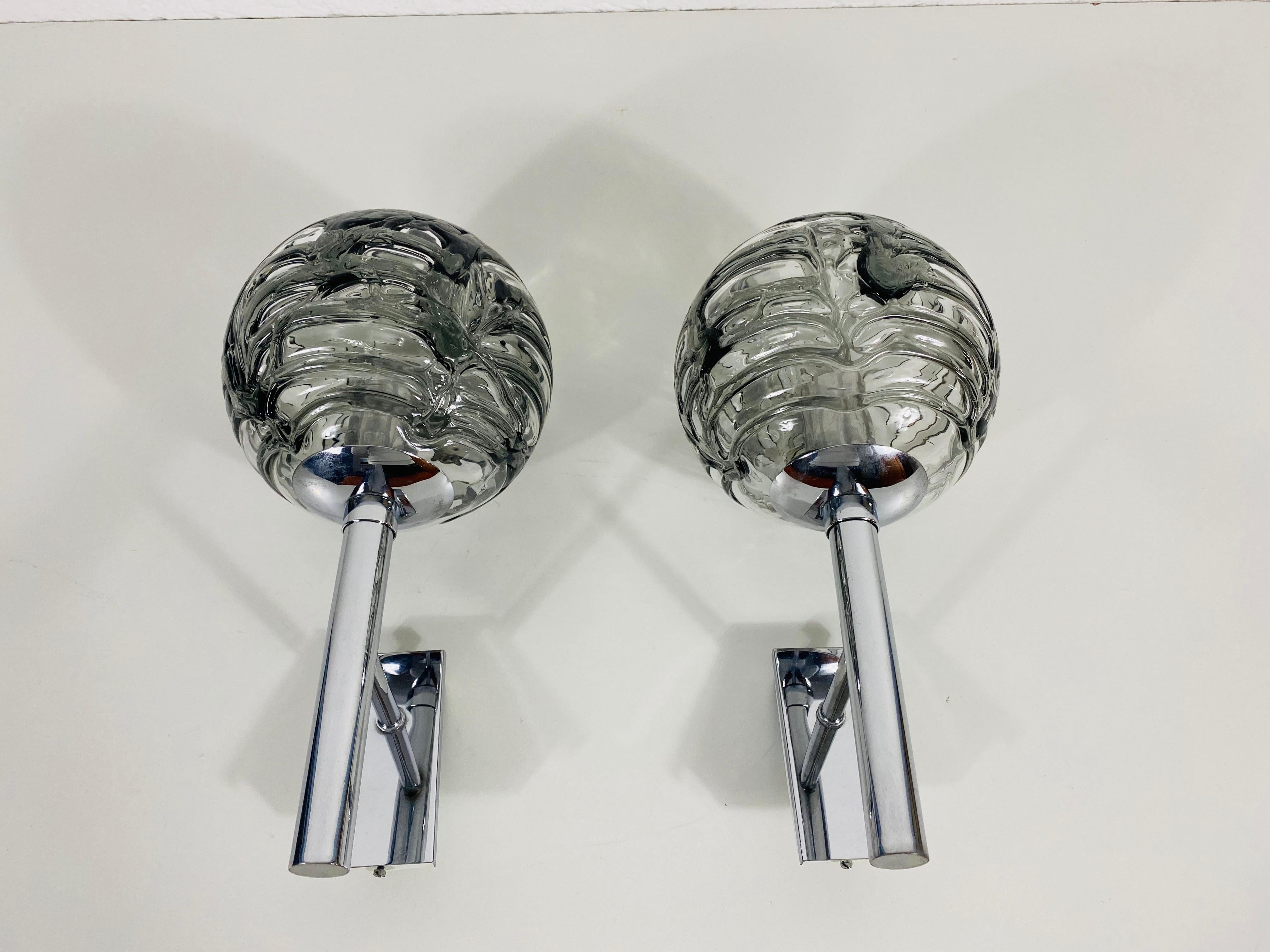 Midcentury pair of beautiful wall lights by the German brand Doria made in the 1960s. They have a beautiful round shape. The unique glass shade is made from Murano glass.

The lightings require E14 light bulbs. Works with both 120/220V. Very good
