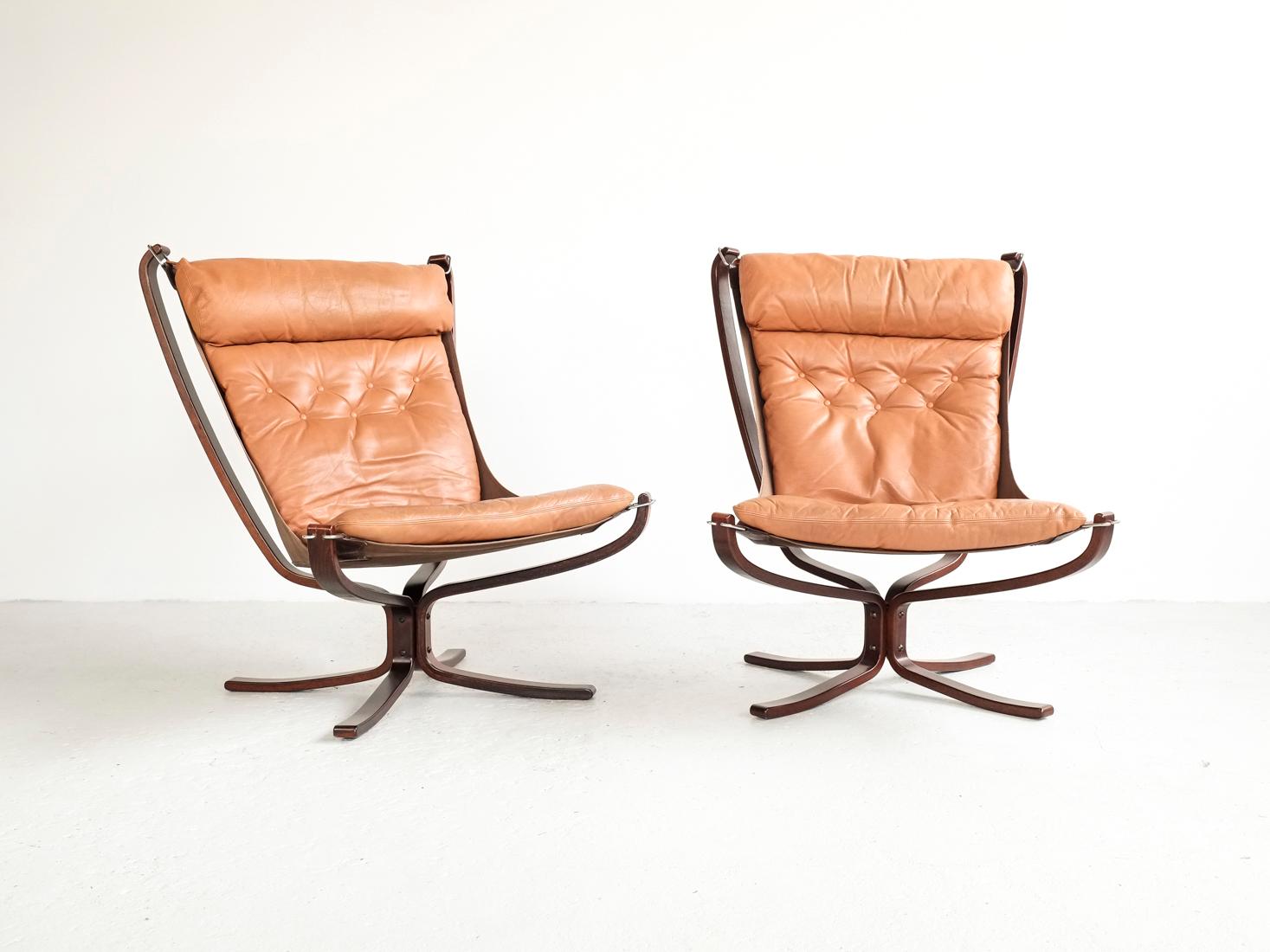 Midcentury pair of Falcon Chairs designed by Sigurd Ressell and manufactured by Vatne Møbler in Norway in the 1970s. It is the model with high back and padded leather. The frame is in dark stained beech, the canvas is dark brown, and the cushion is