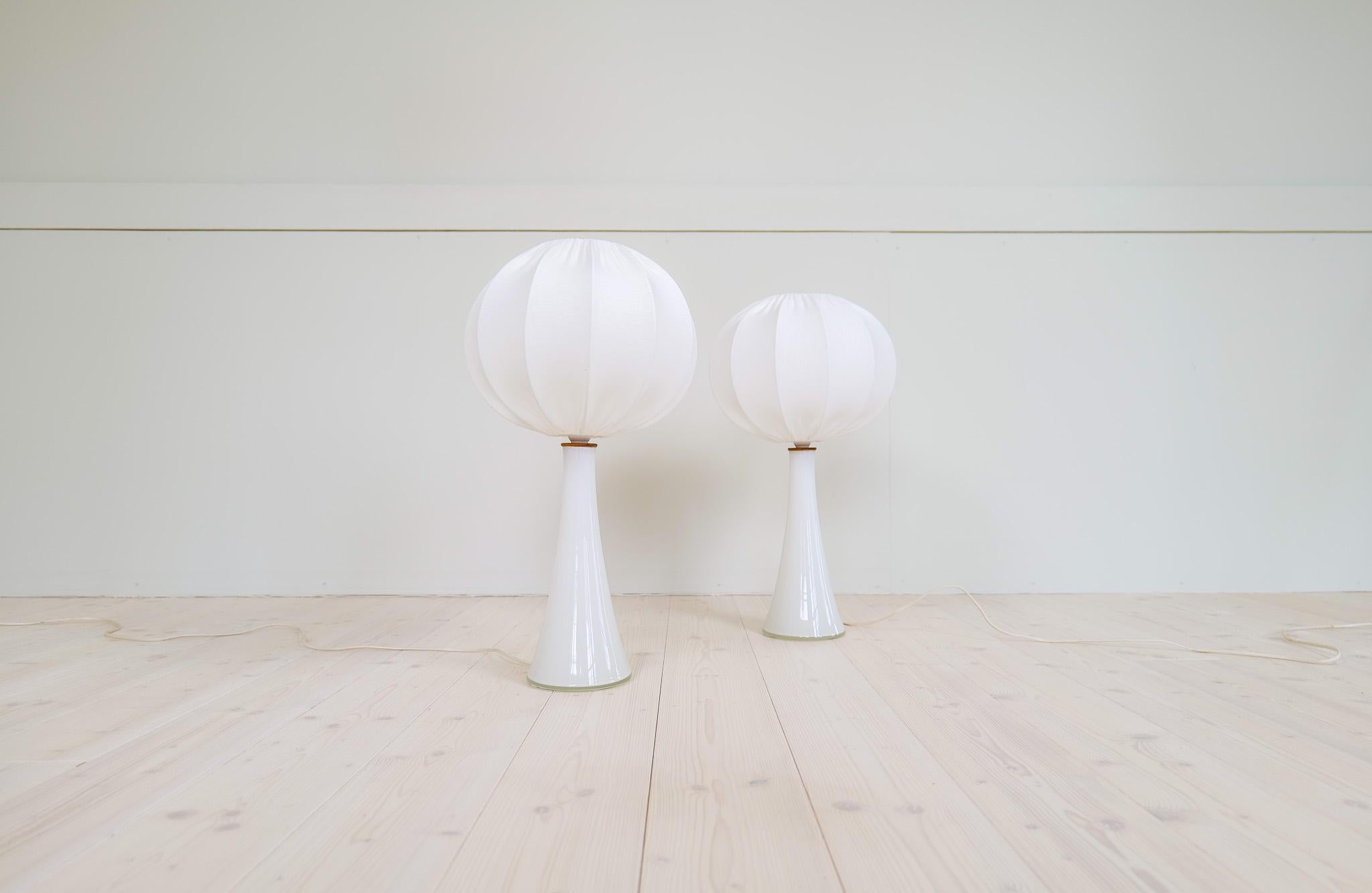 A pair of diabolos shaped Swedish opaline glass table lamps with teak fittings. Designed by Berndt Nordstedt for Bergboms. 

Good working vintage condition. All new cotton shades. 

Dimensions: H 59 cm, W 30 cm, Base 15 cm. Shades H 23 cm Width