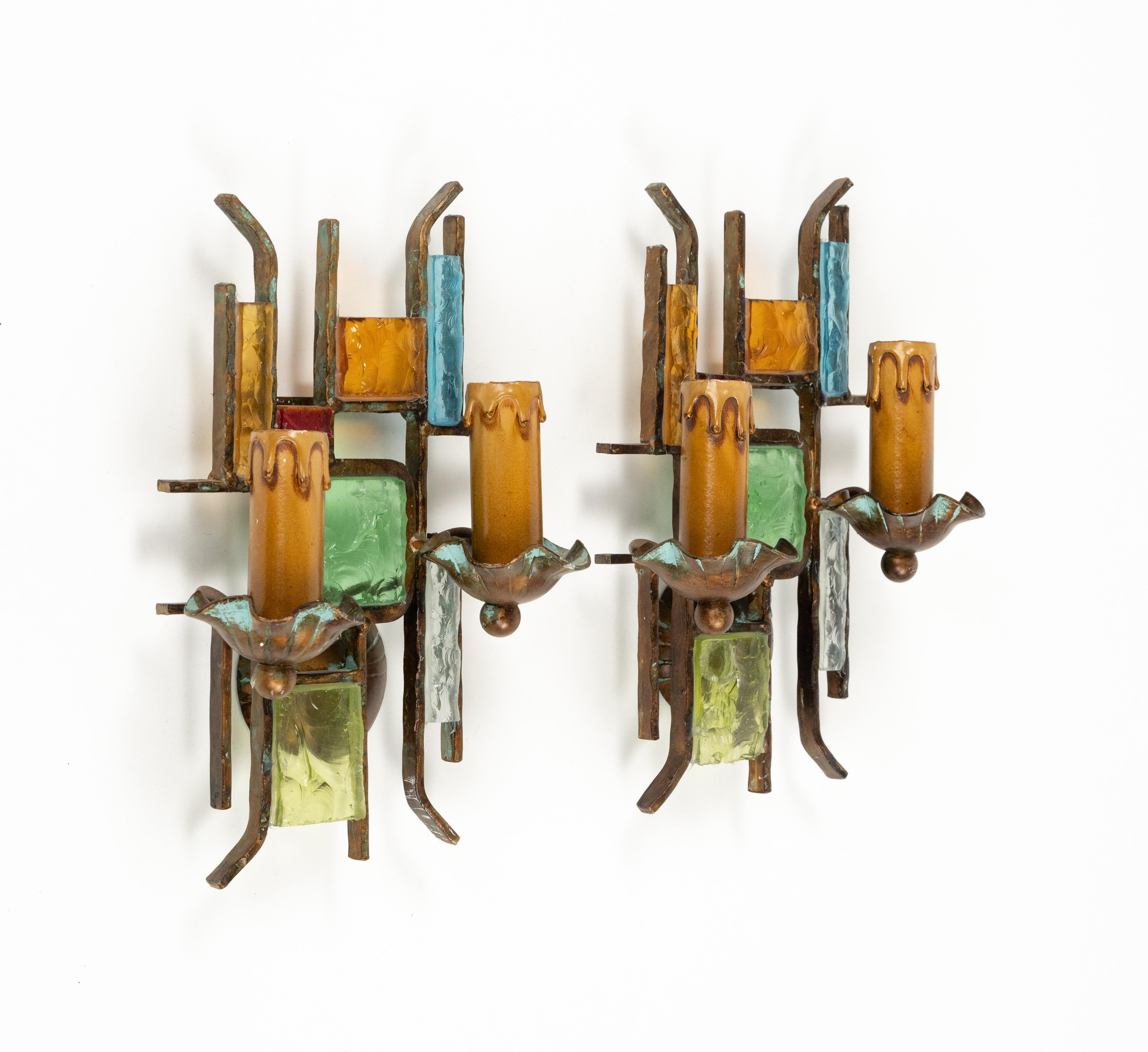 Midcentury amazing pair of wall lamp sconces in bronze wrought iron and multi-color hammered glass produced by Poliarte.  

Made in Italy in the 1970s.  

The color of the glasses enclosed by the iron makes a wonderful light situation on the wall. 
